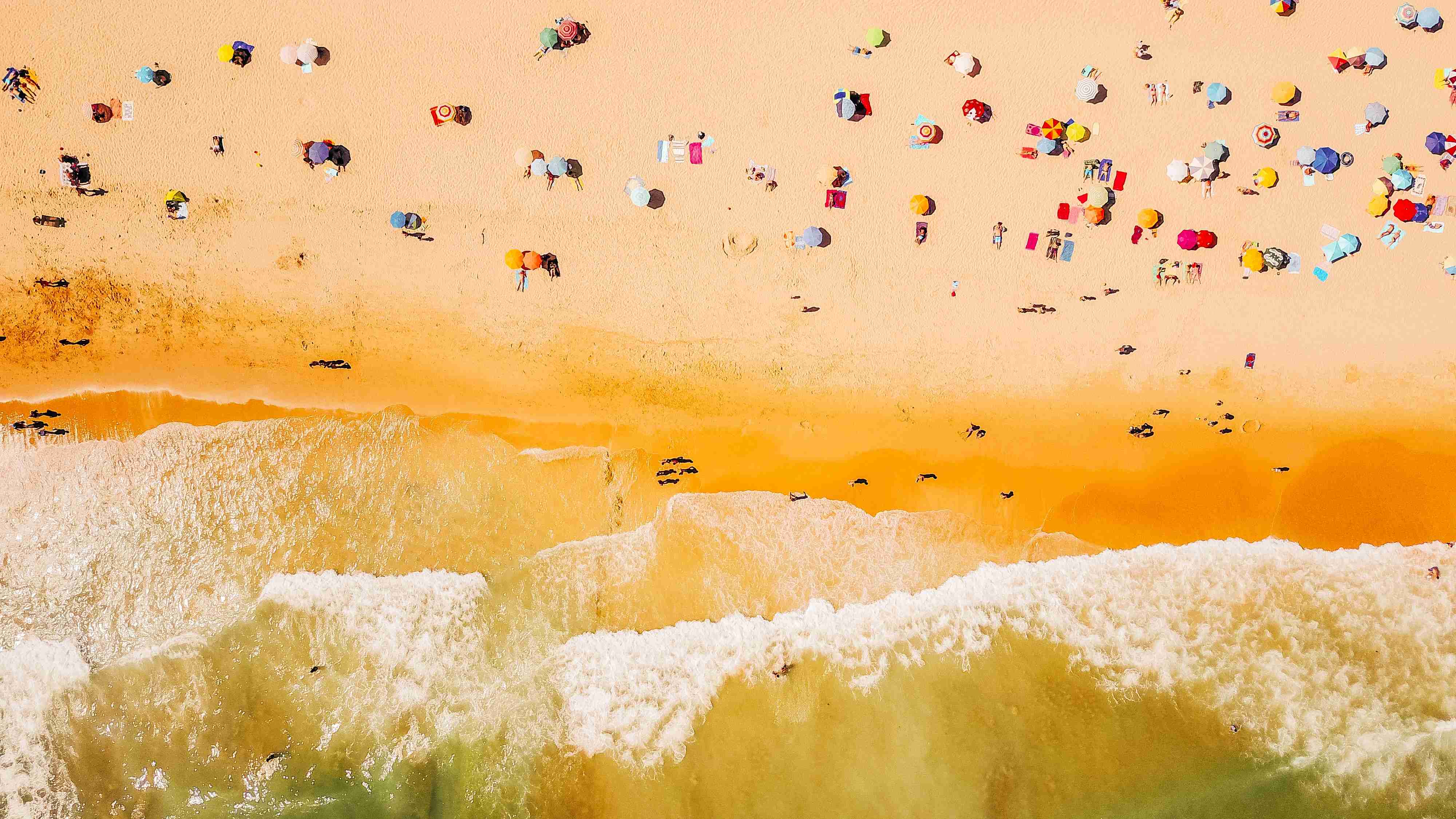 Въздушен изглед на плаж с чадъри и вълни