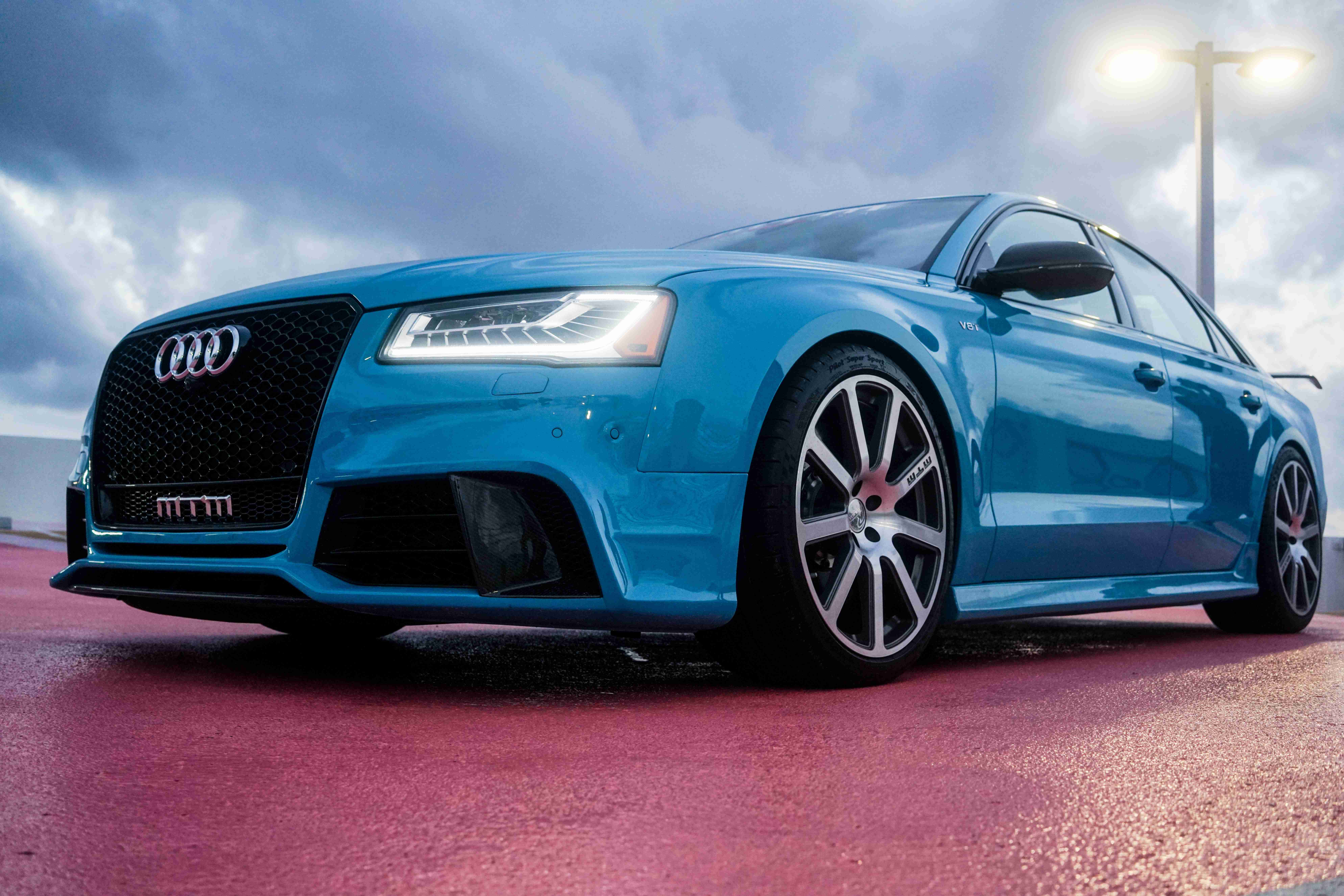 Audi RS5 Coupe Biru Di Atas Turapan Basah Di Bawah Lampu Jalan