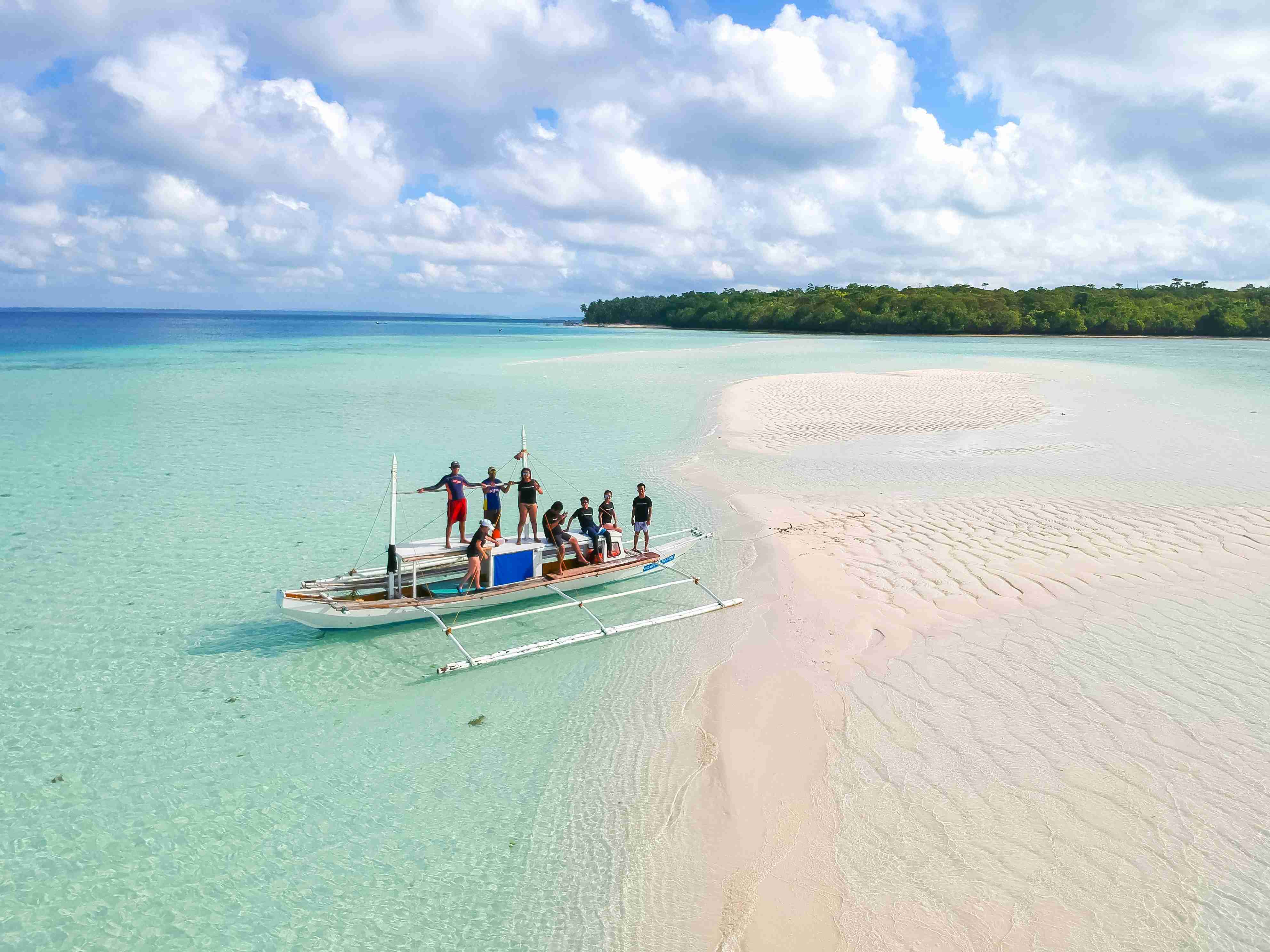 Barco e turistas na costa arenosa
