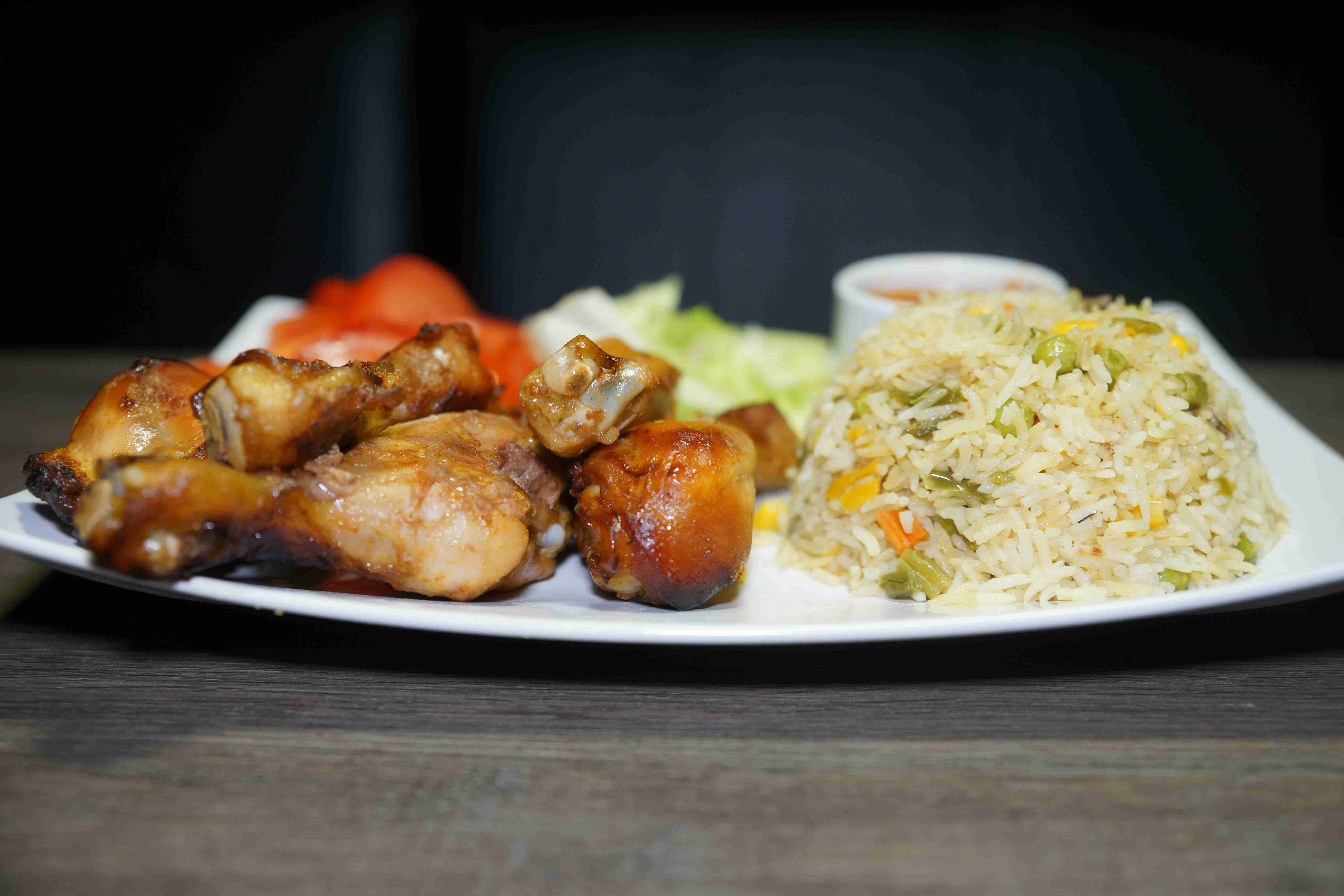 प्लेट पर फ्राइड राइस और सलाद के साथ ग्रिल्ड चिकन विंग्स