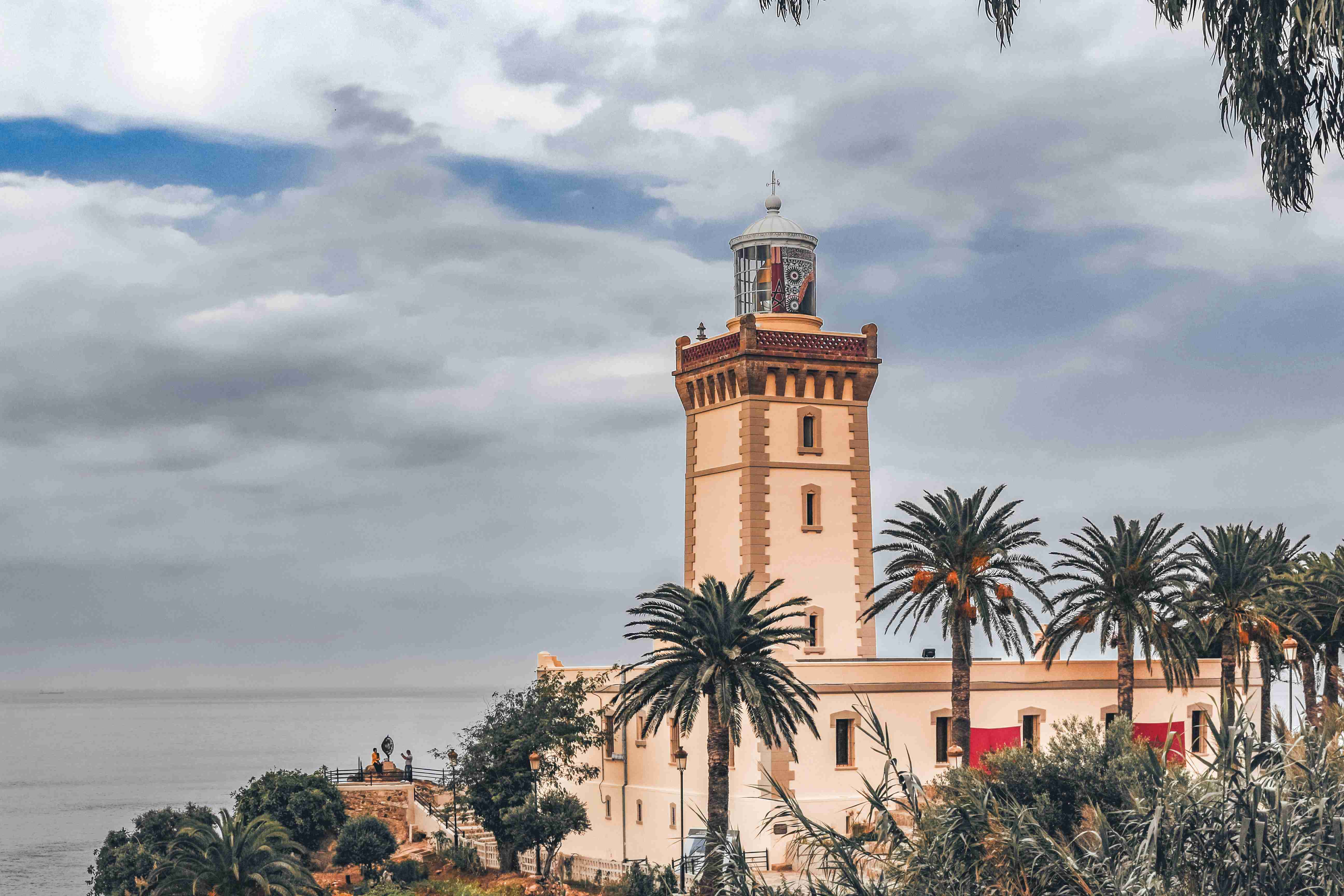 Lighthouse Among Palms with Cloudy Sky Backdrop
