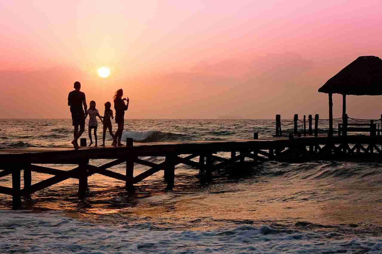 Silhouetted family enjoys a stroll on the beach pier