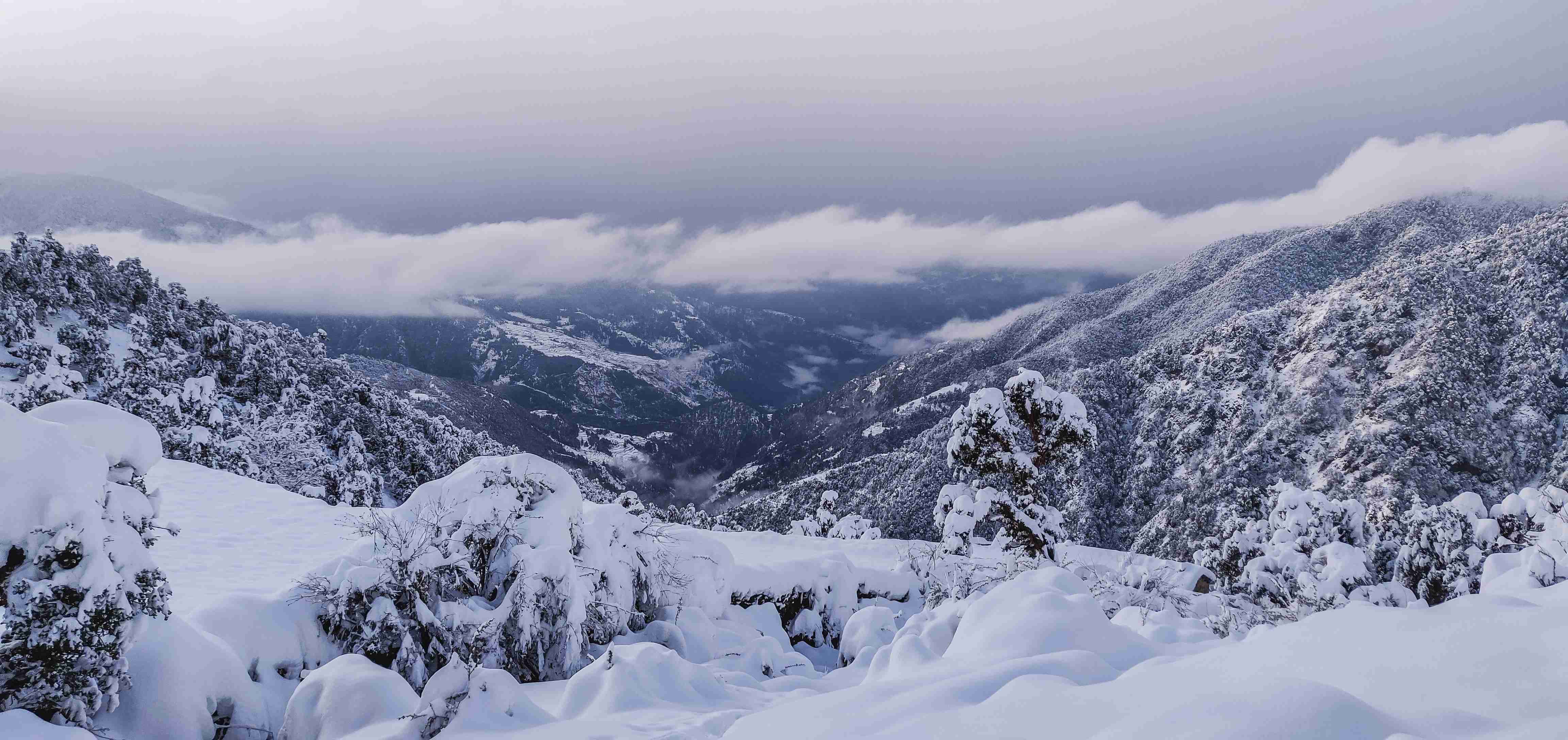 Snow Covered Mountain Valley with Low Clouds