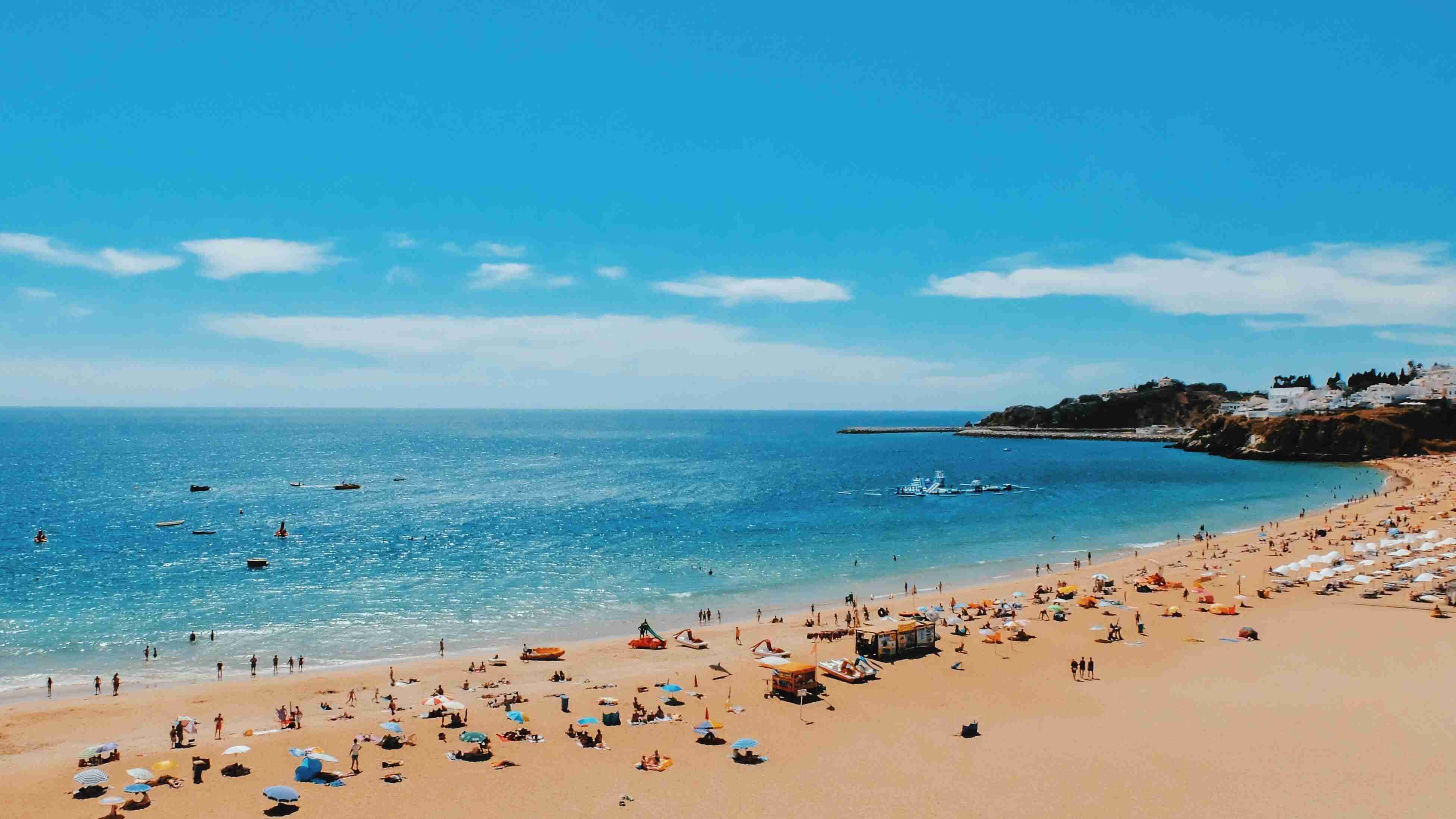 Journée ensoleillée sur la plage avec foule et bateaux