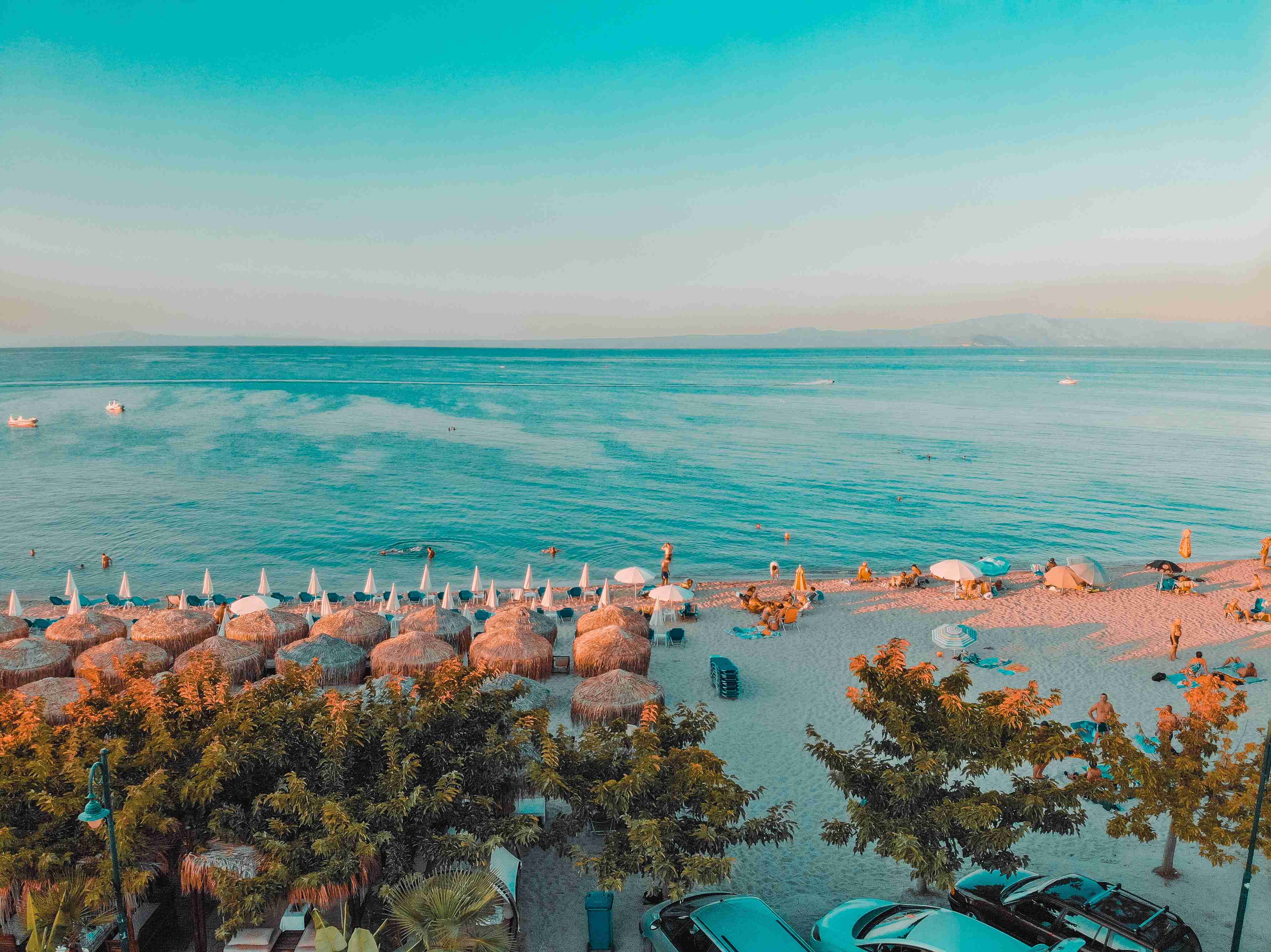 Suasana Sunset di Pantai dengan Payung Jerami dan Laut Tenang