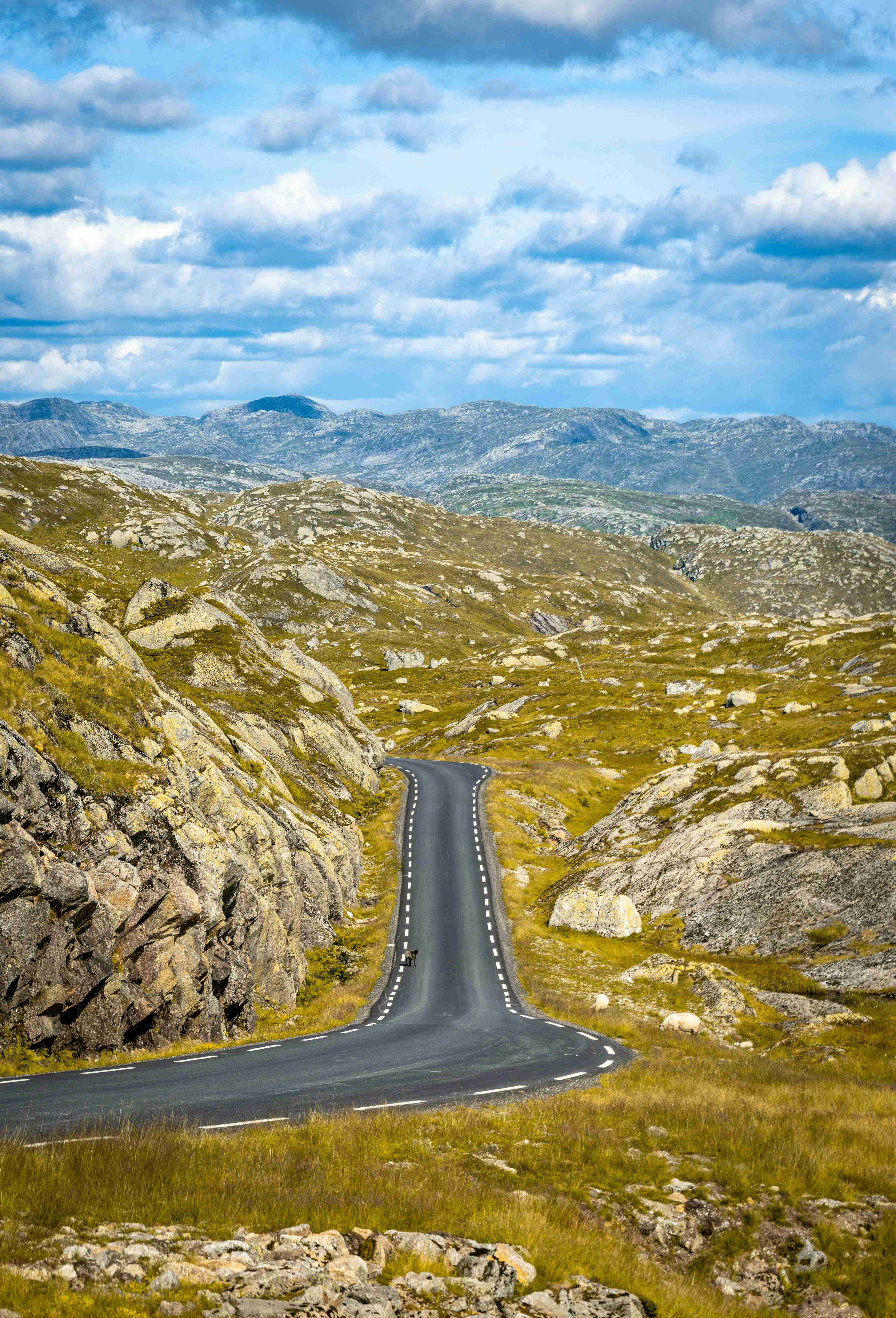 Winding Mountain Road with Scattered Clouds