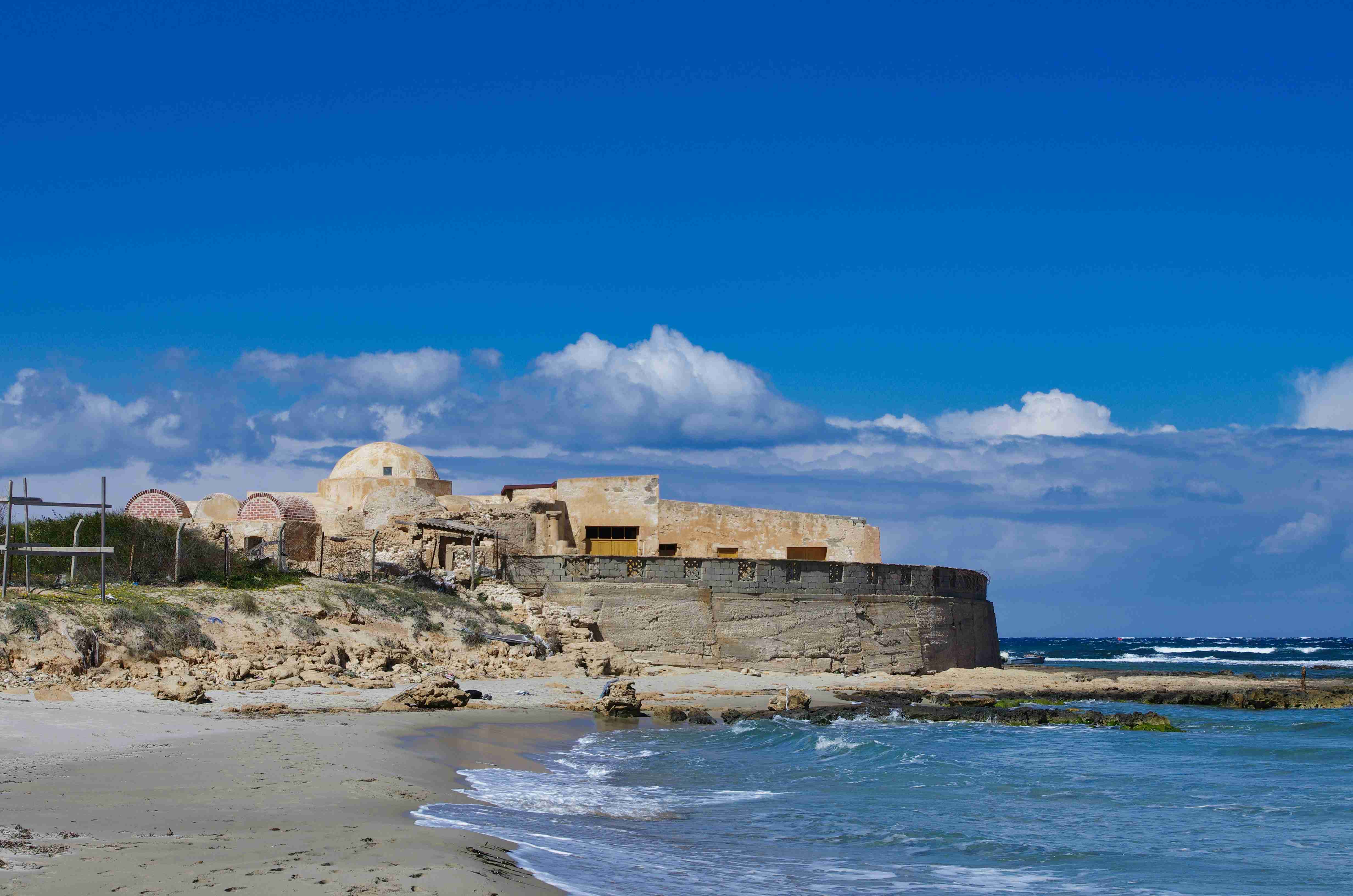 brown concrete building near sea under blue sky