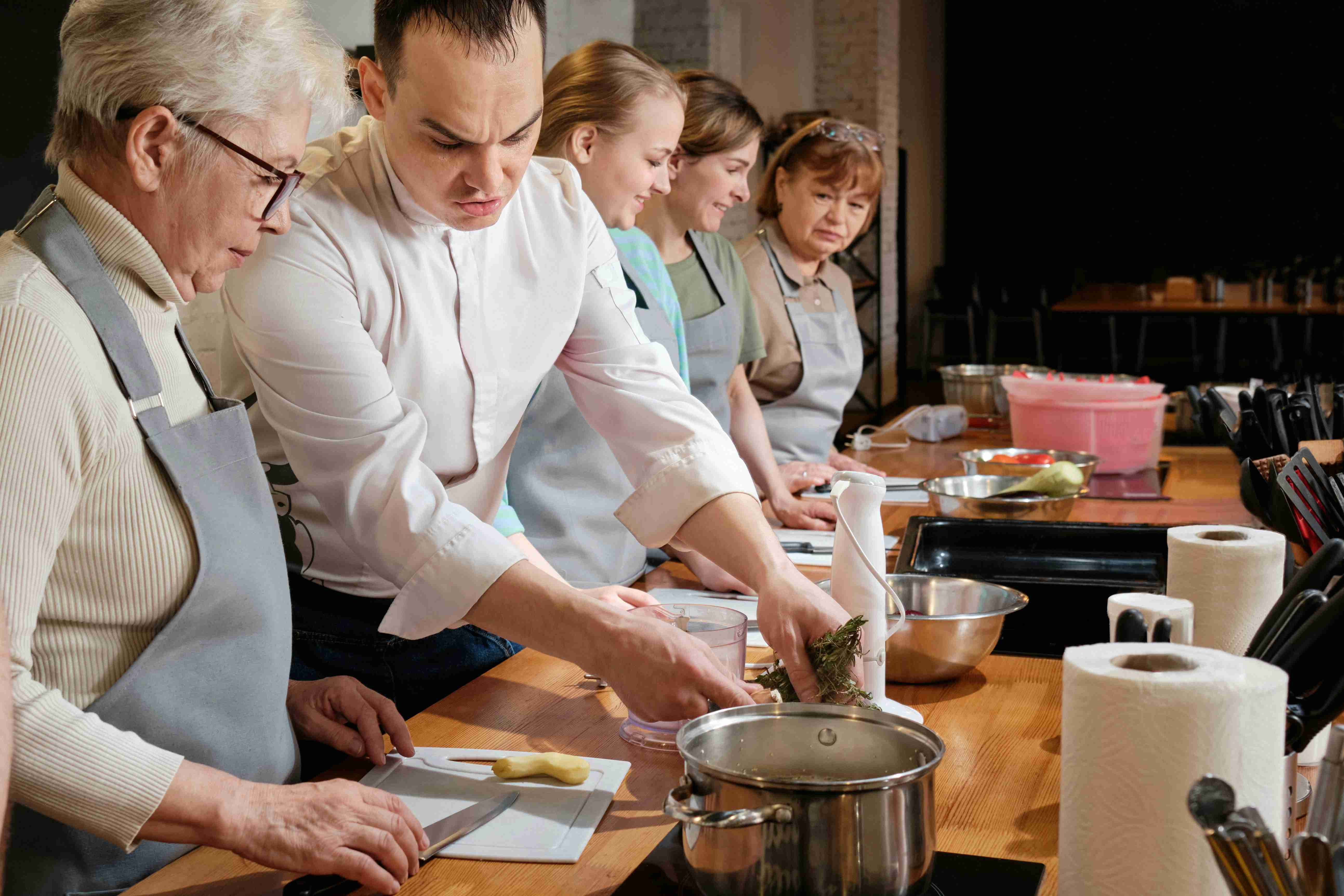/a-group-of-people-standing-around-a-table-preparing-food