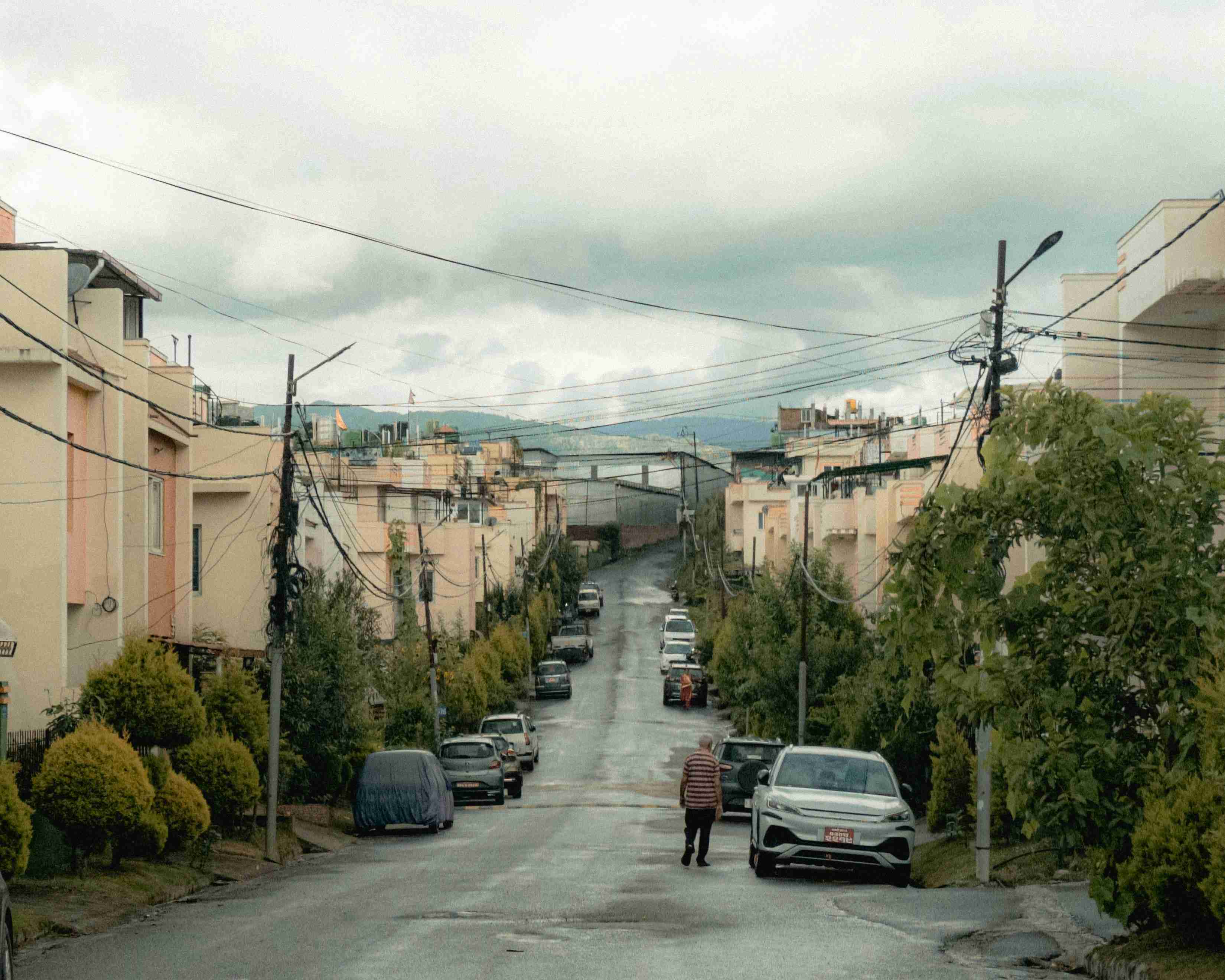 egy férfi sétál az utcán parkoló autók mellett