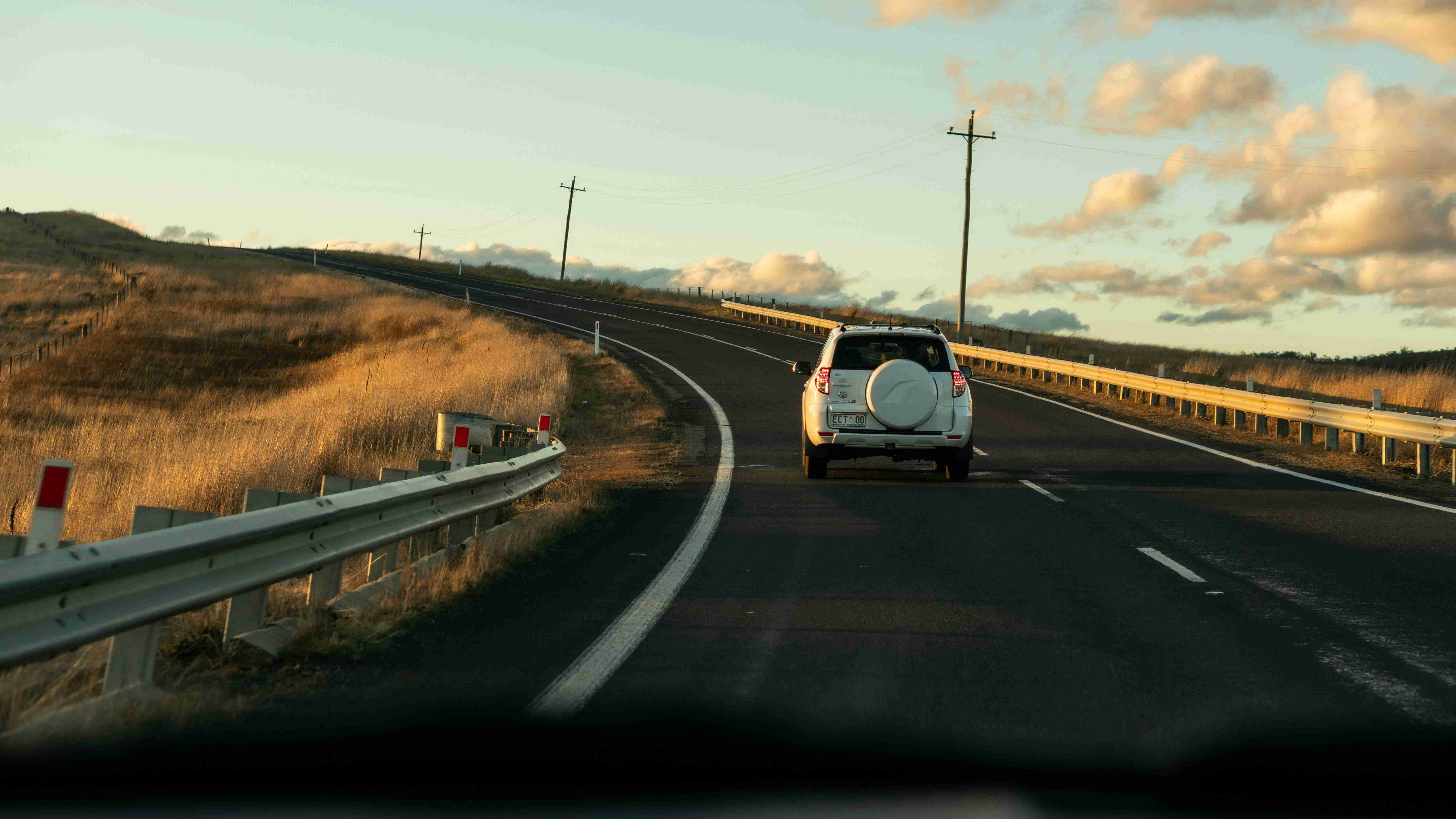 un camion bianco che percorre una strada accanto a una collina