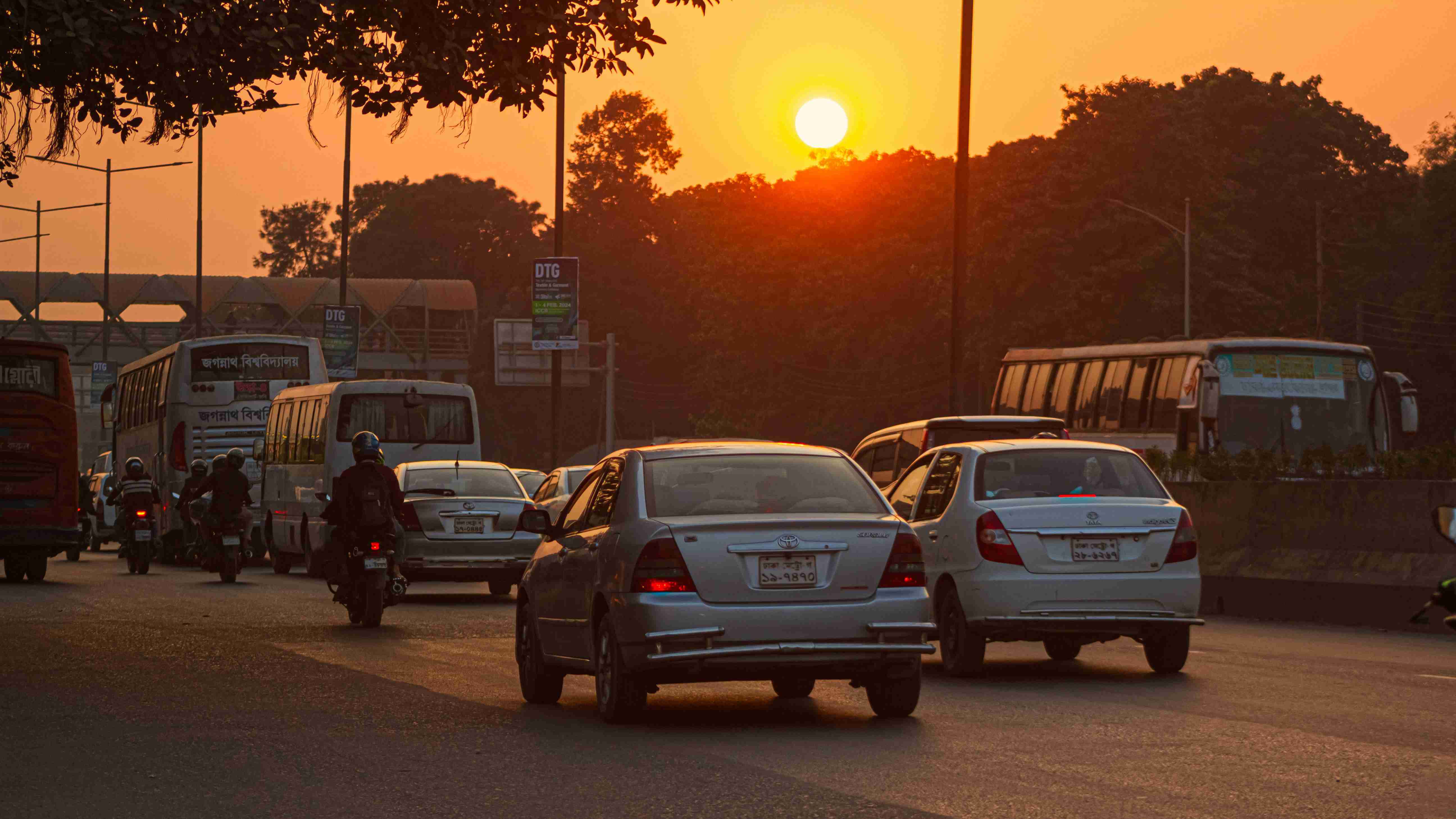 eine Gruppe von Autos fährt bei Sonnenuntergang eine Straße entlang