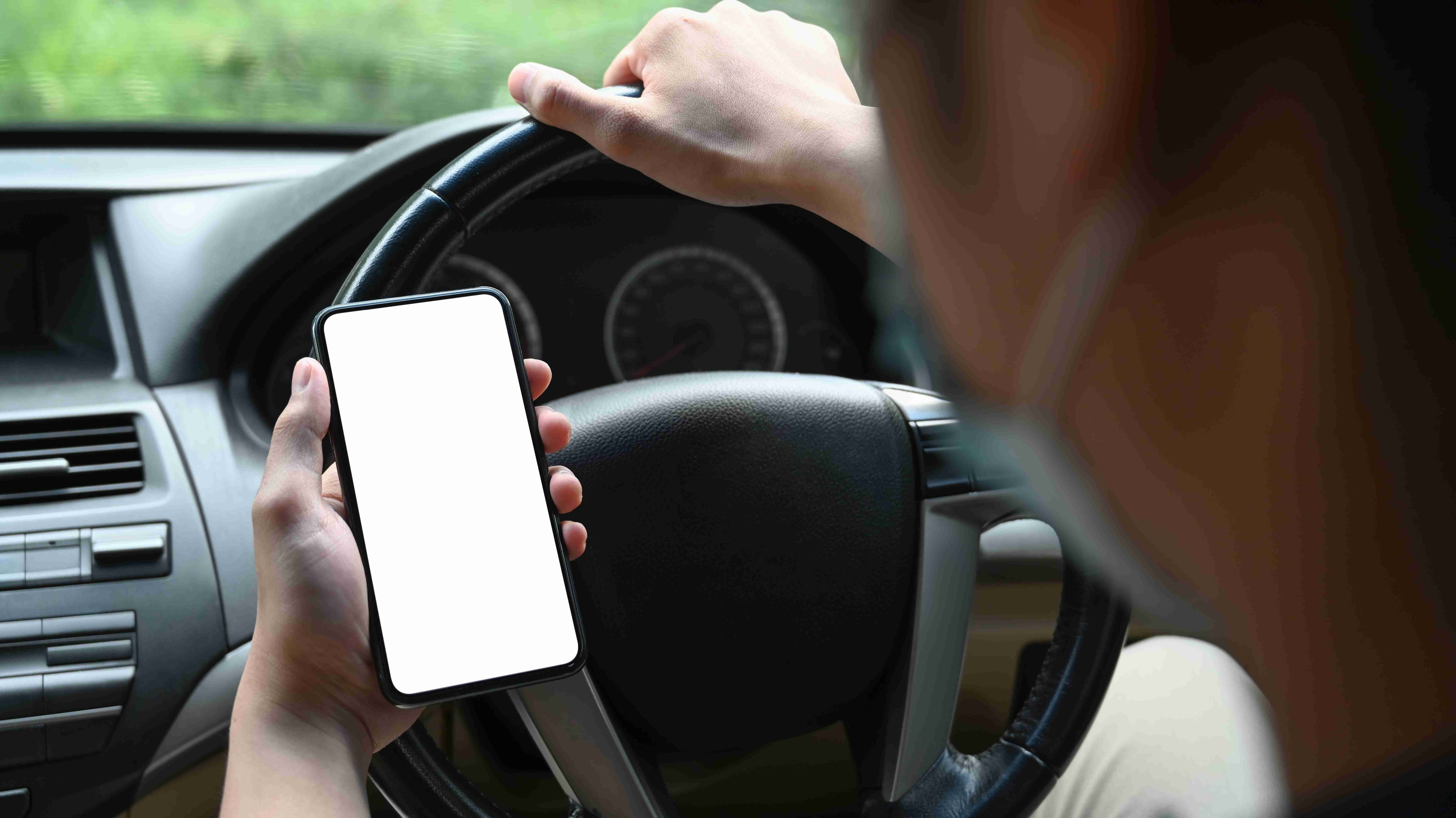 Közelkép egy üzletemberről, aki védőmaszkot visel és mobiltelefont használ autóvezetés közben