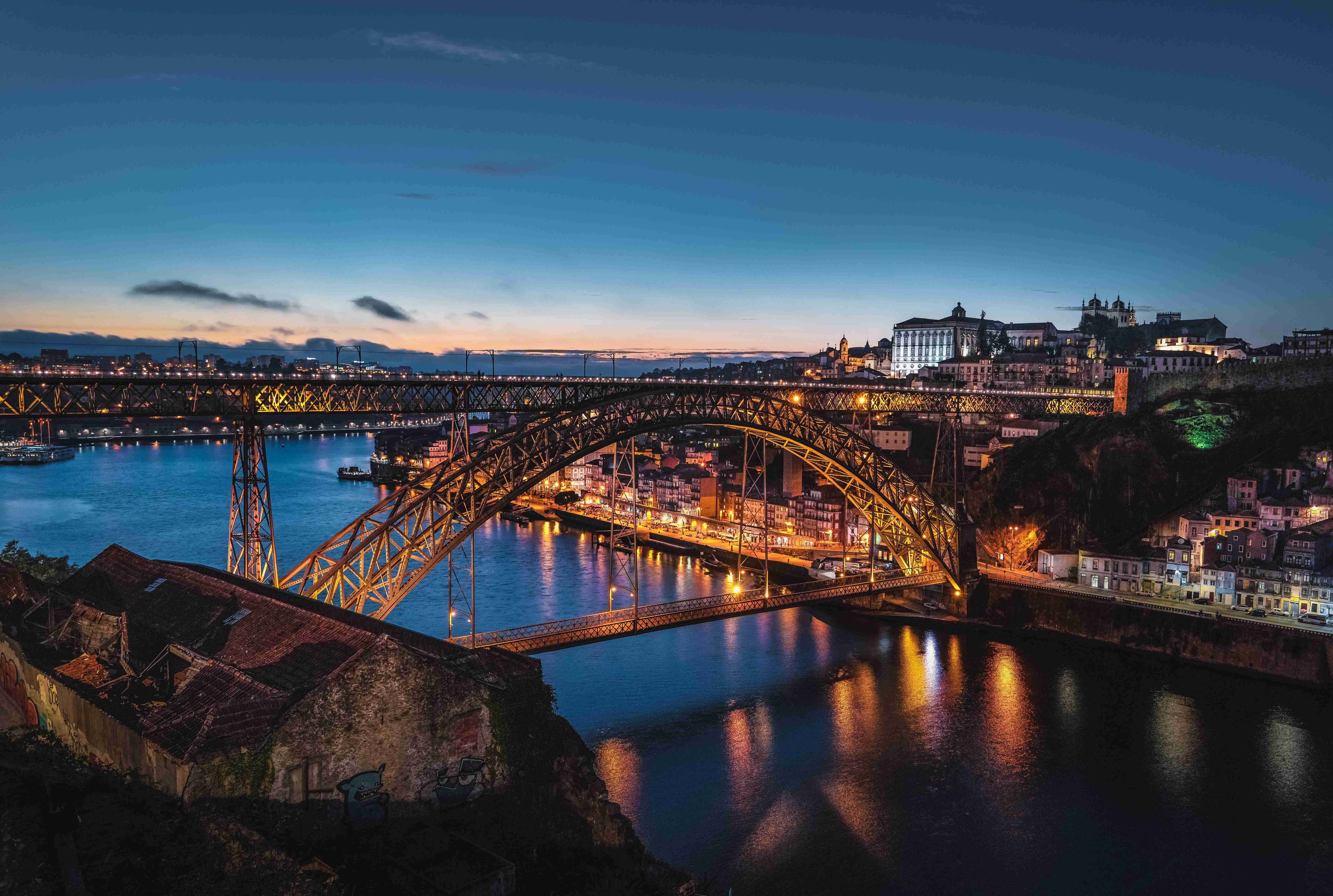 Crépuscule sur le pont Dom Luís I à Porto, avec paysage urbain illuminé et rivière.