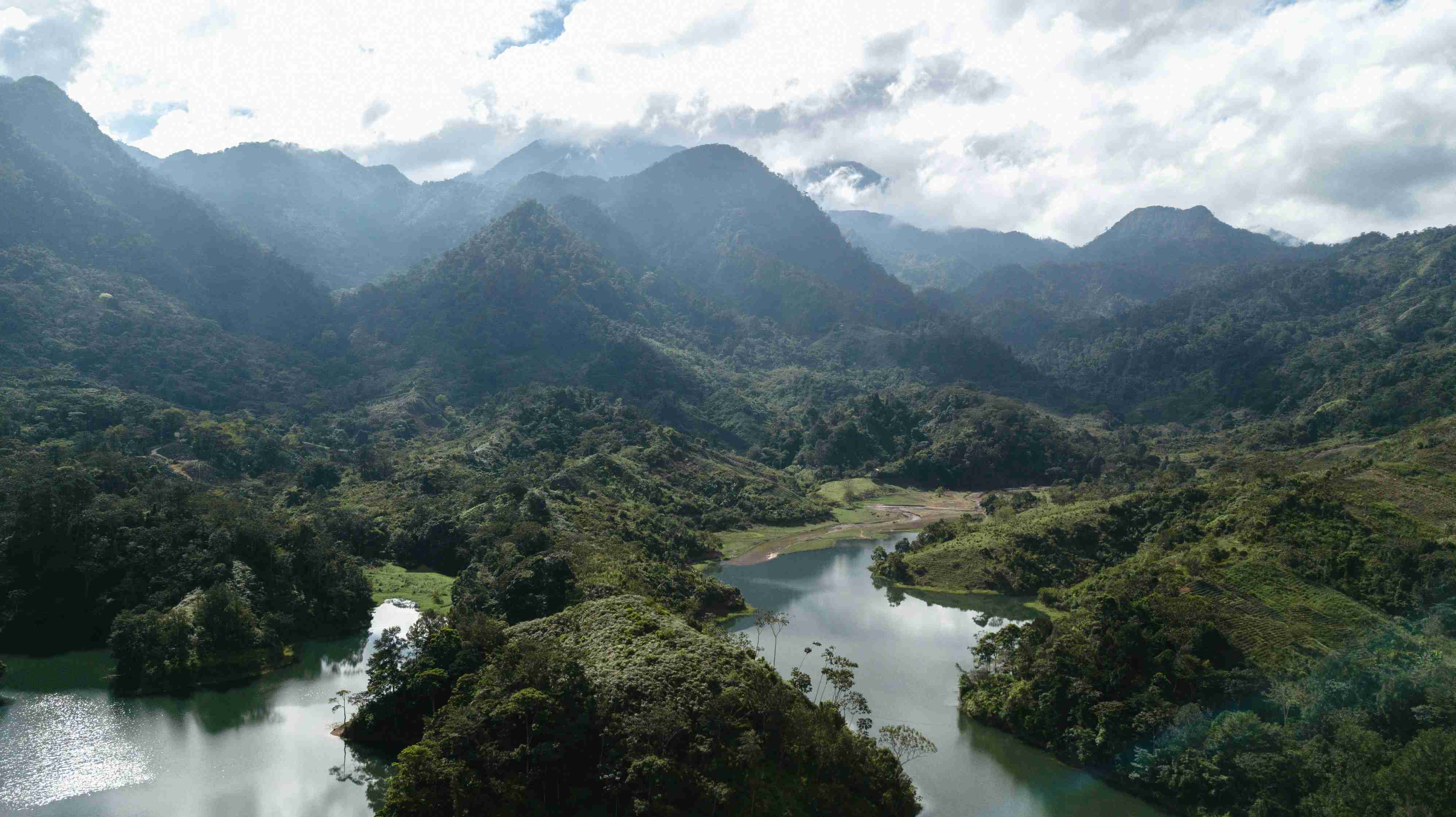 green-mountains-and-river-under-white-clouds-during-daytime