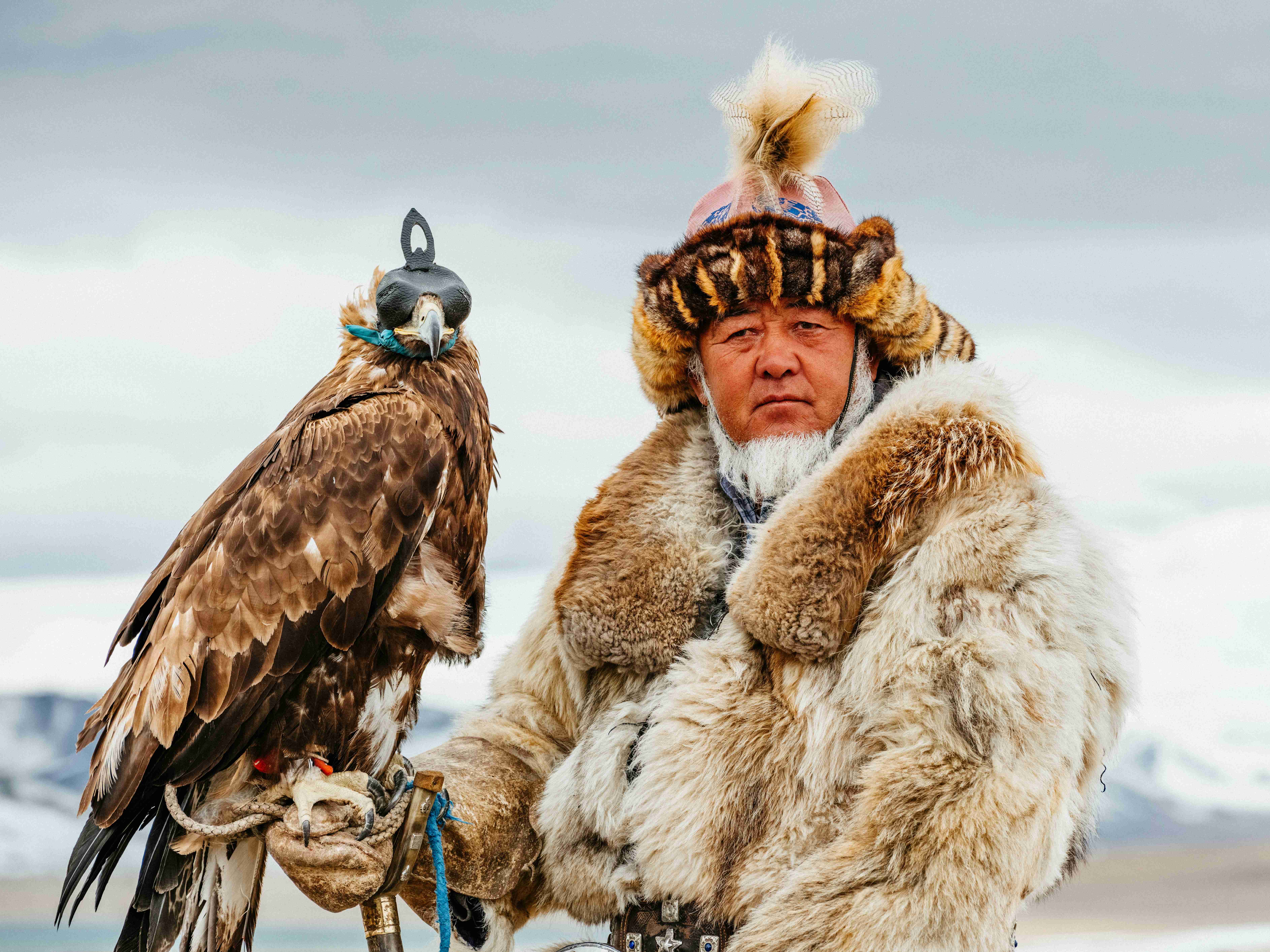 a man in a fur coat holding a bird