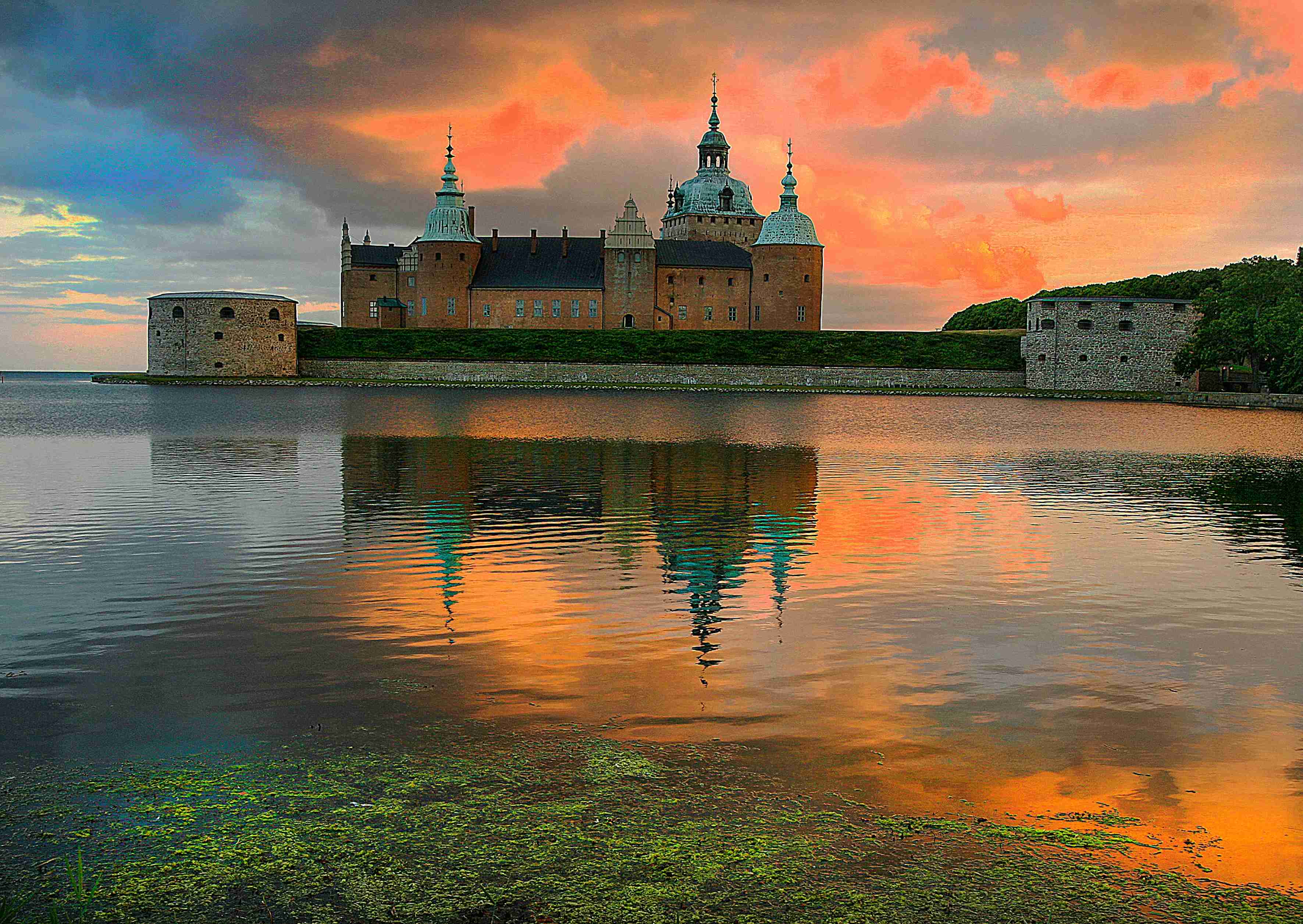 a-large-castle-sitting-on-top-of-a-lake-under-a-cloudy-sky
