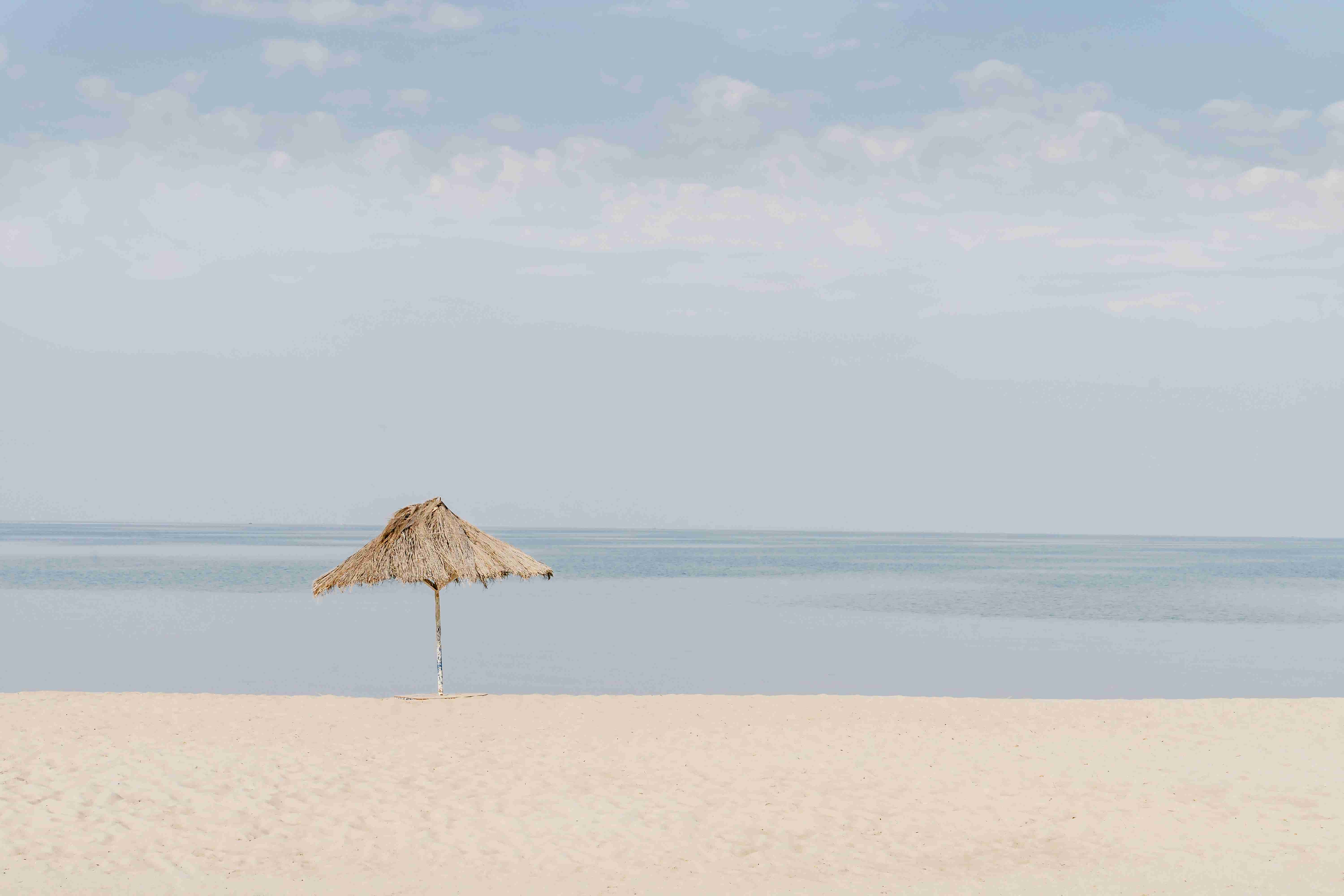 brown beach umbrella on white sand during daytime