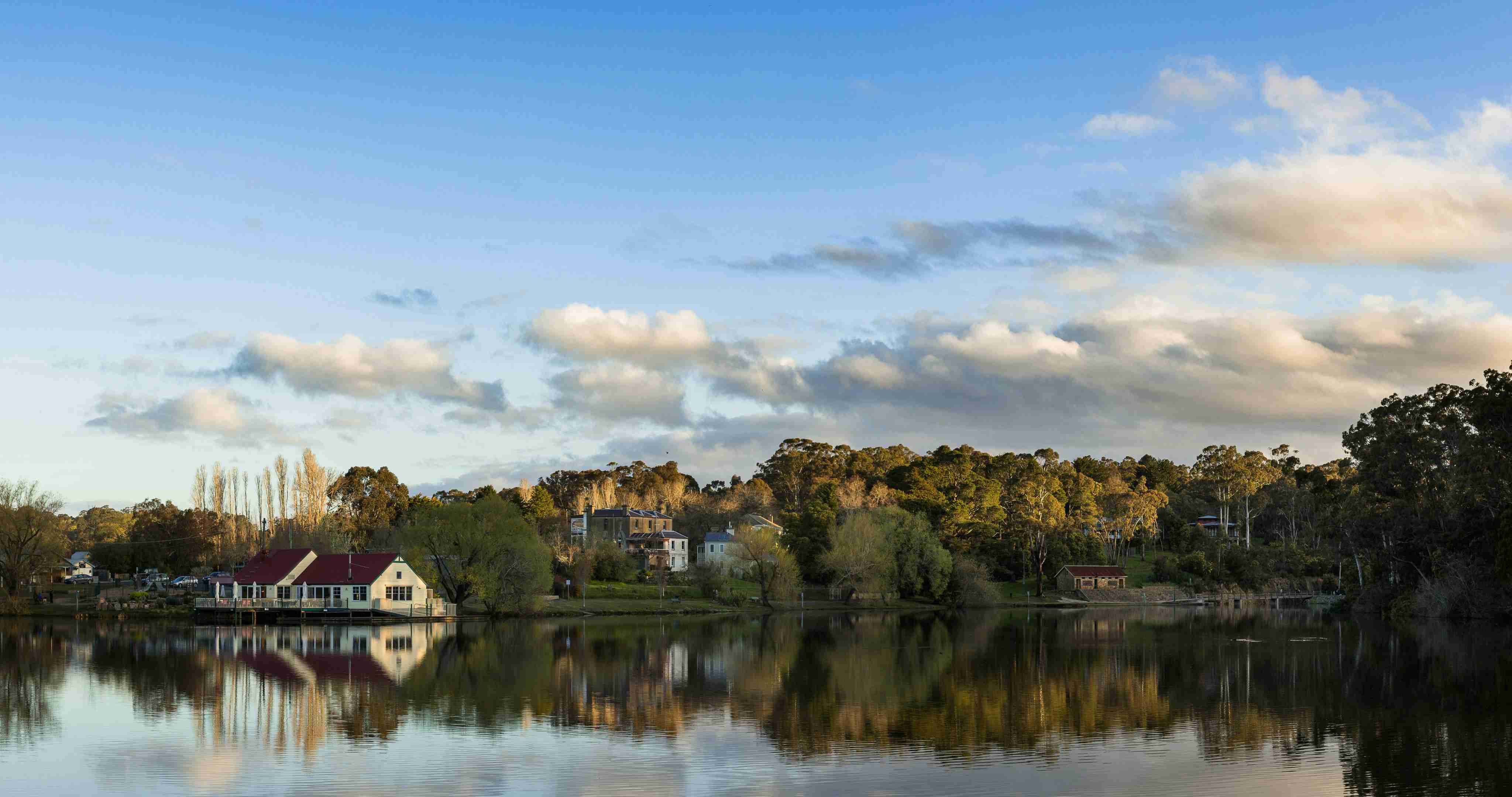 white-and-red-house-near-body-of-water-under-blue-sky-during-daytime