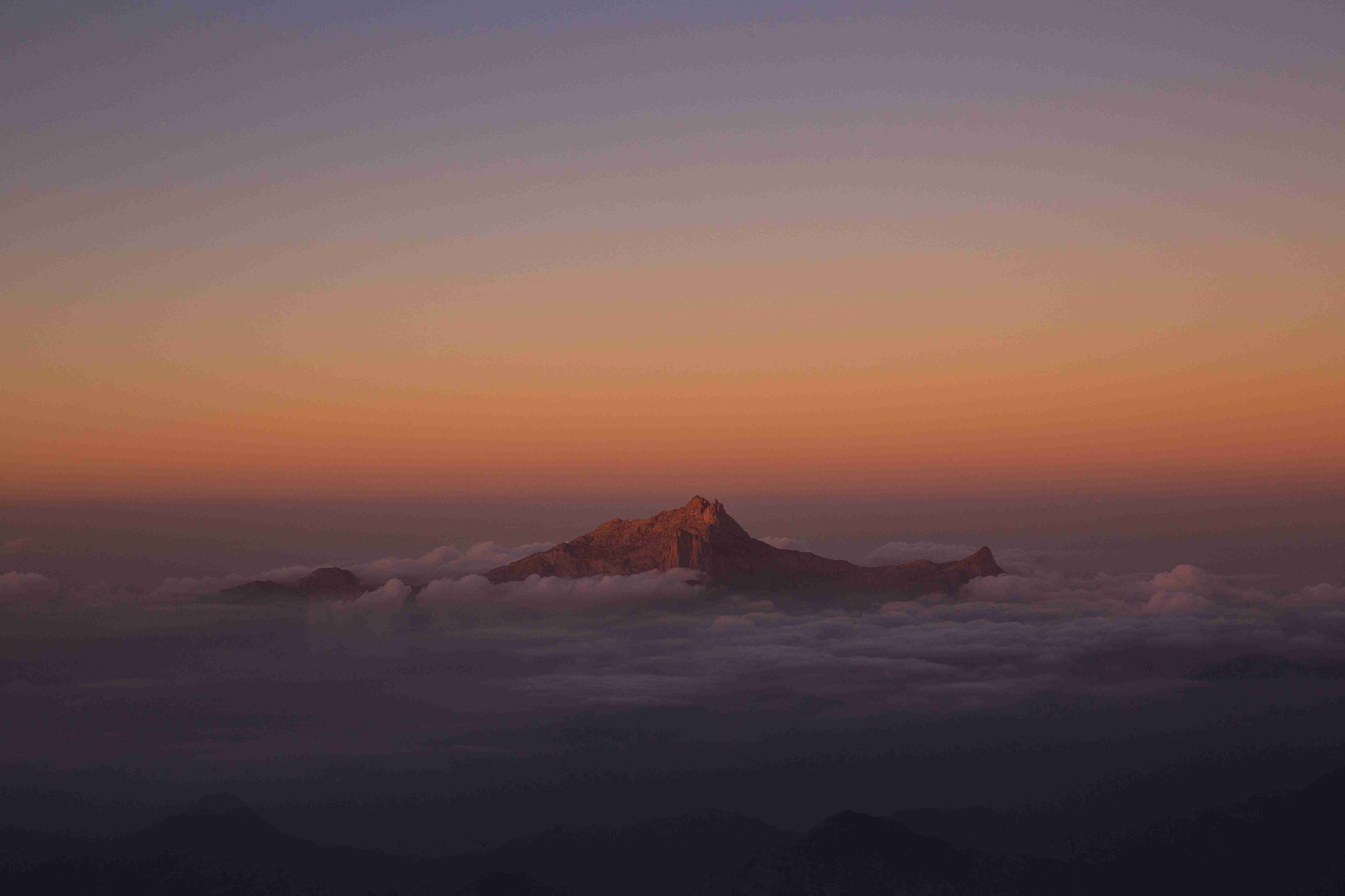 berg bedekt door wolken tijdens zonsondergang