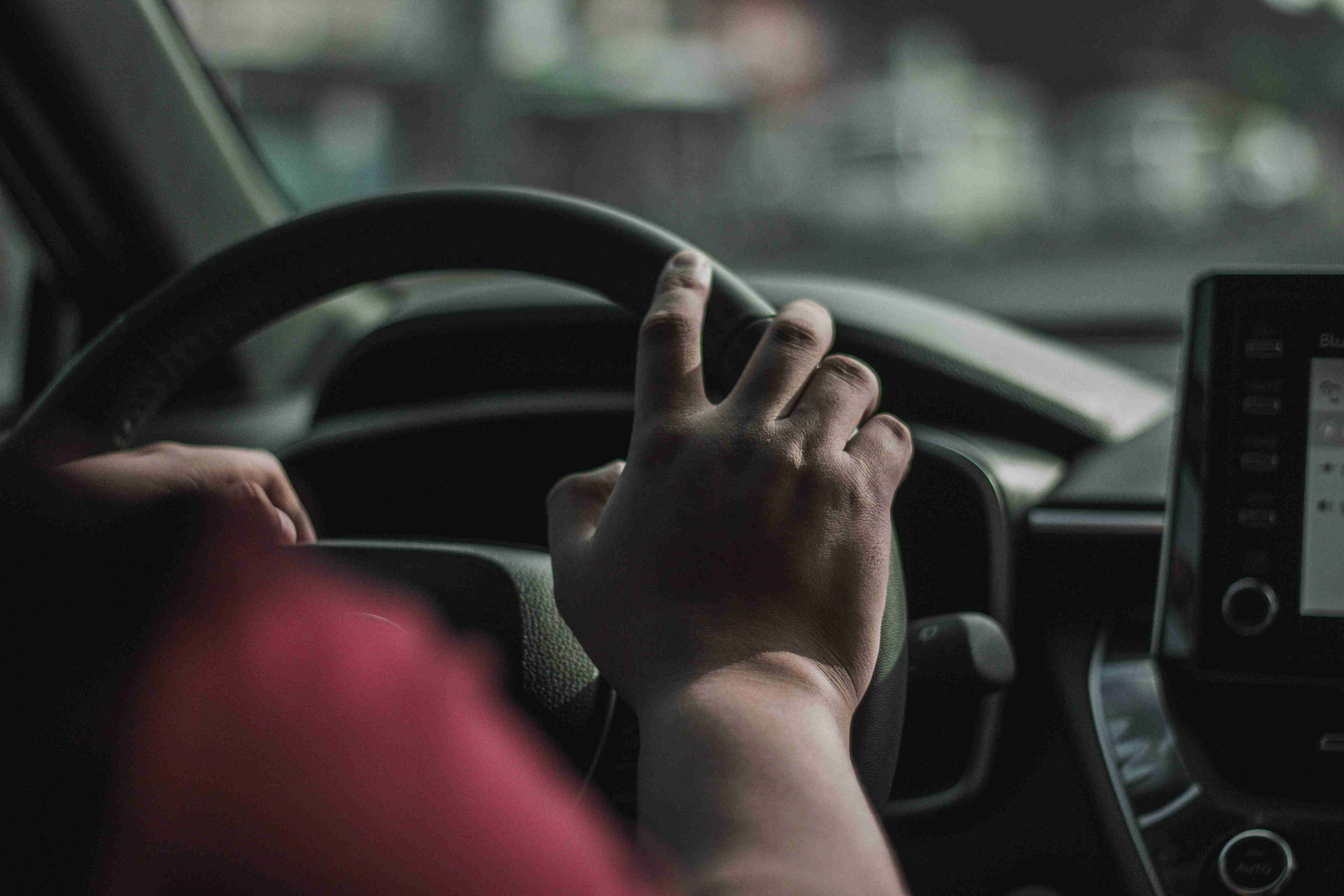 una persona che guida un'auto con la mano sul volante