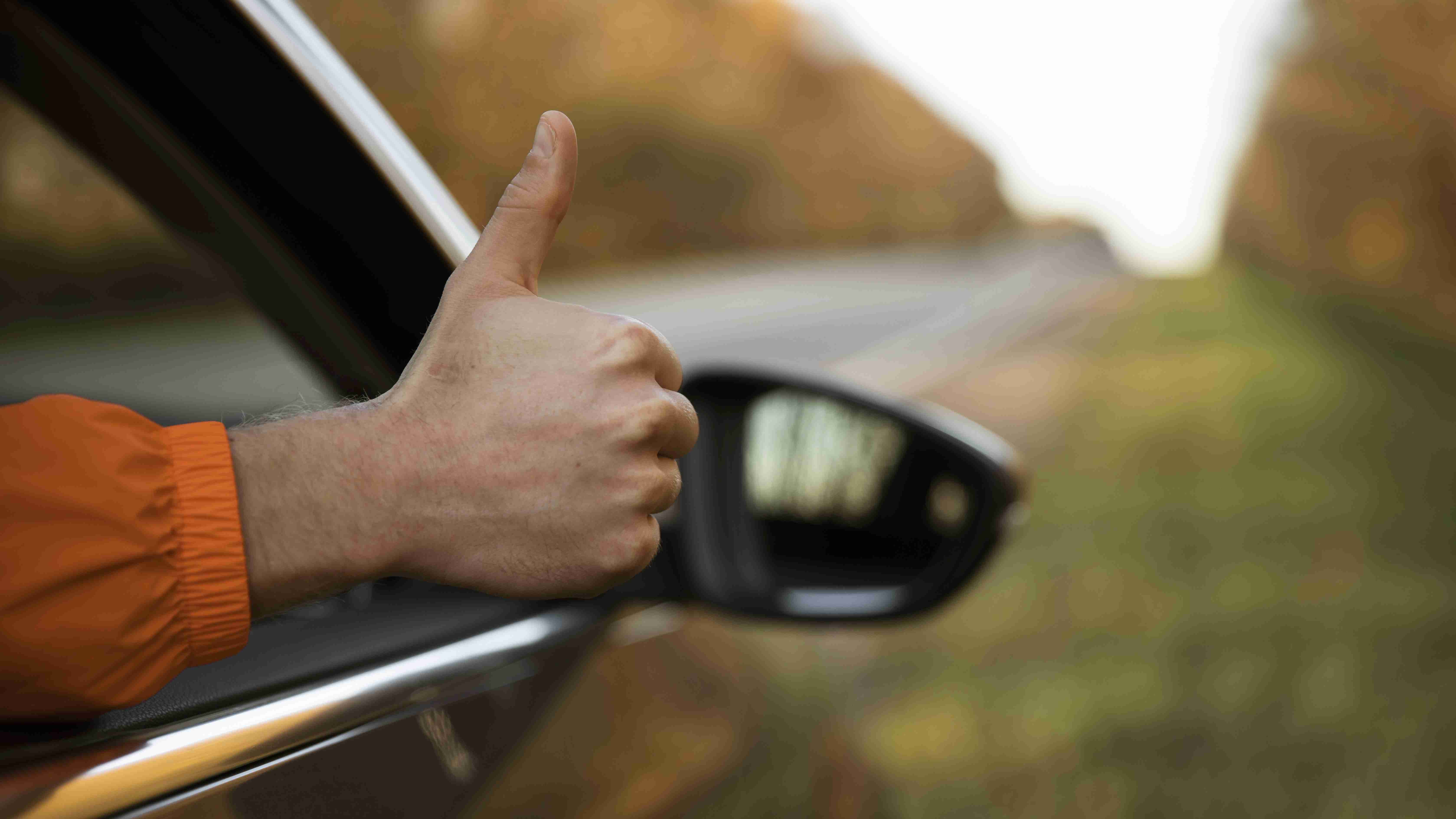 man giving thumbs-up out his car