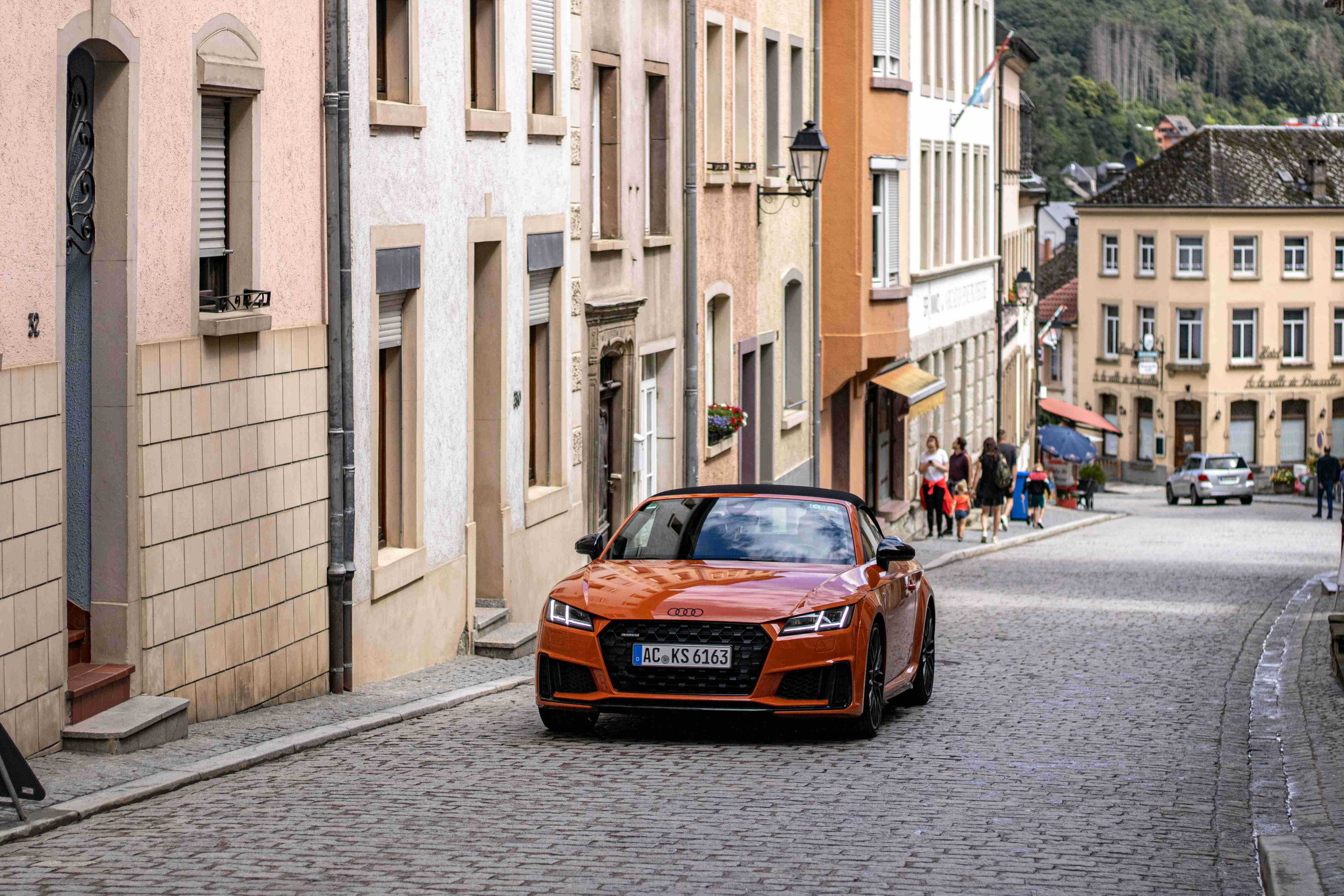 an orange car is parked on a cobblestone street