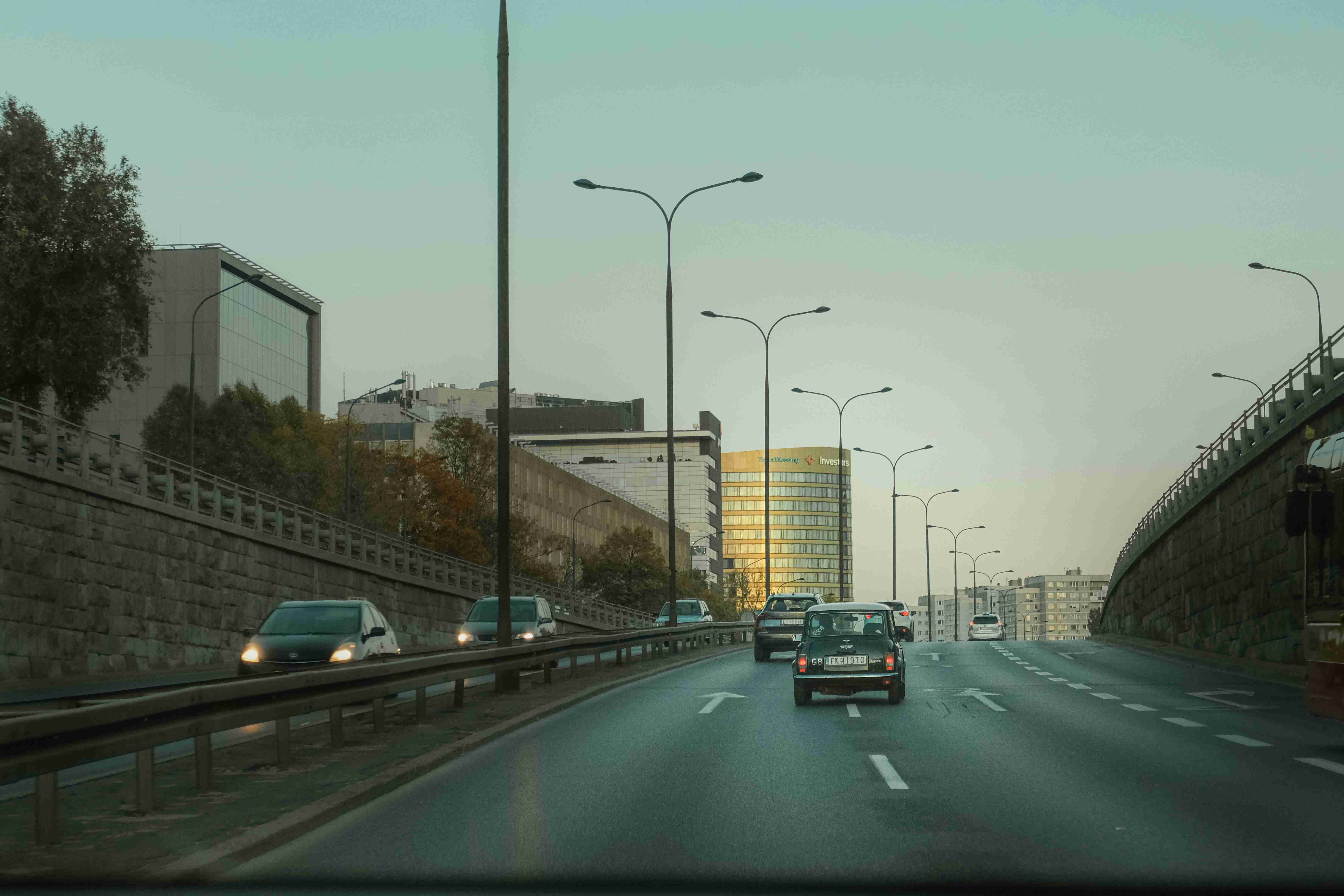 en bil, der kører ned ad en motorvej ved siden af høje bygninger