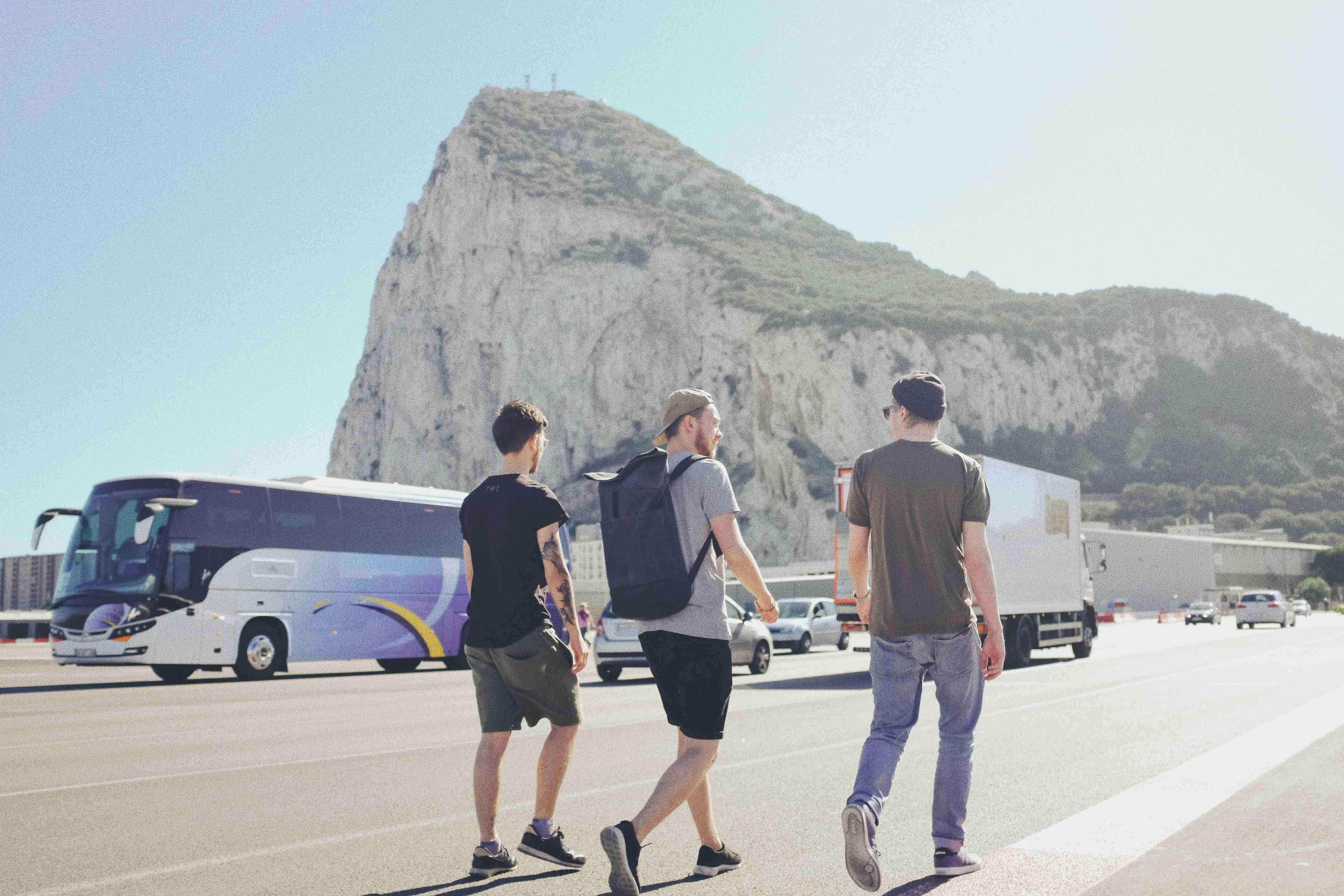 tři muži kráčející po ulici poblíž vozidel