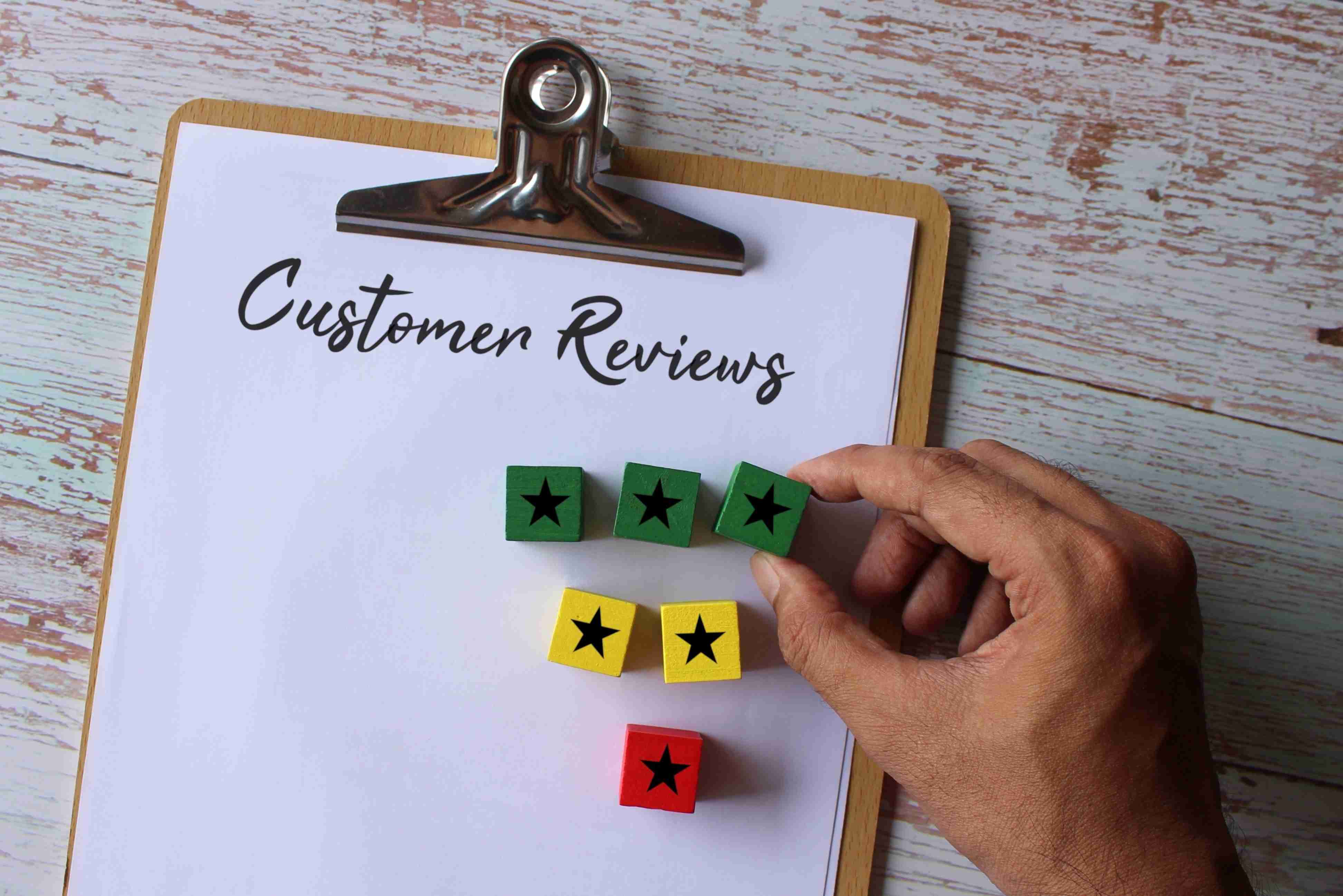 Paper clipboard with text Customer Reviews and wooden cube with star icon