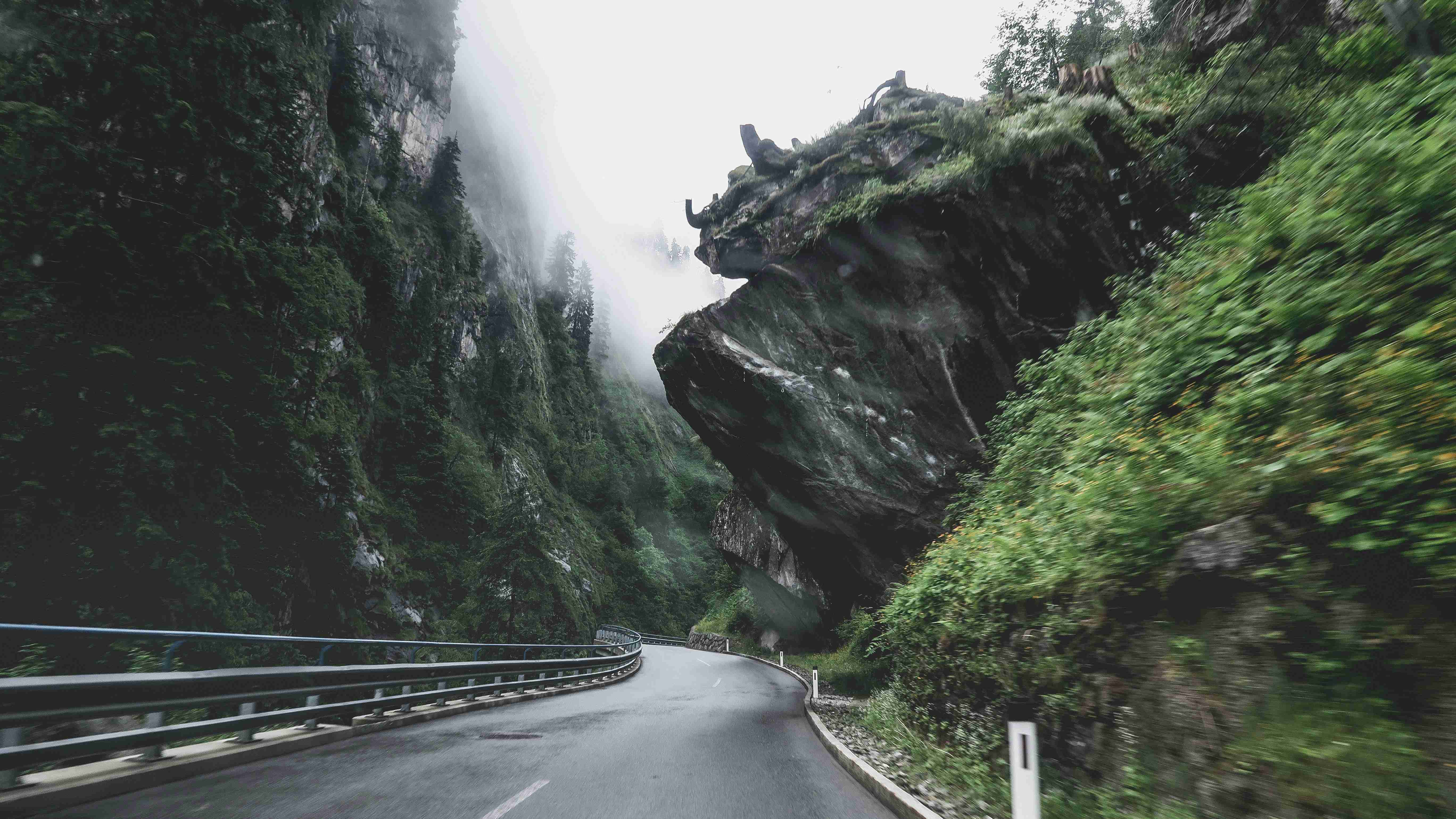 black-asphalt-road-between-green-and-brown-rocky-mountain-during-daytime