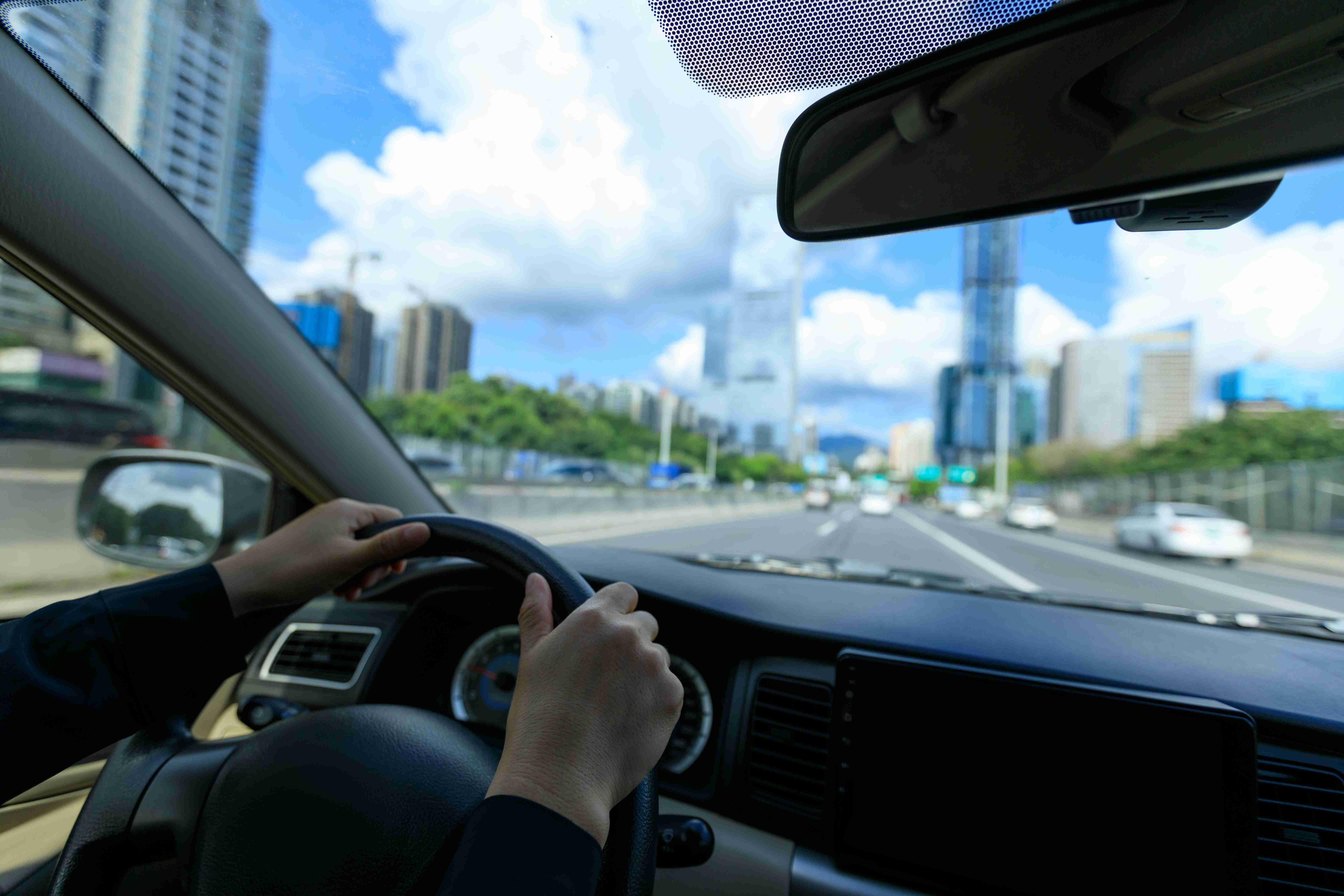 शहर की सड़क पर कार चलाते लोग