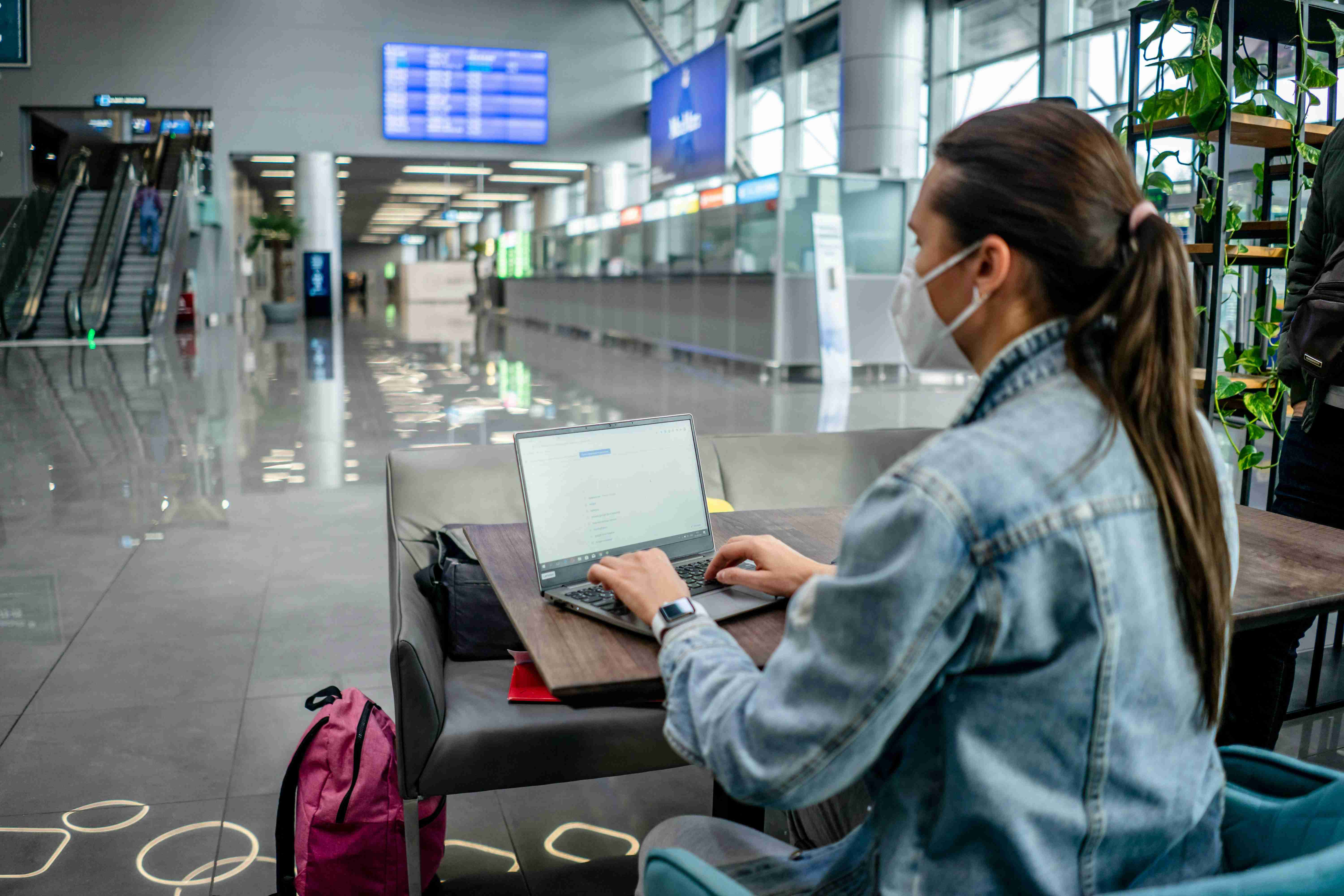 focused woman in mask browsing laptop