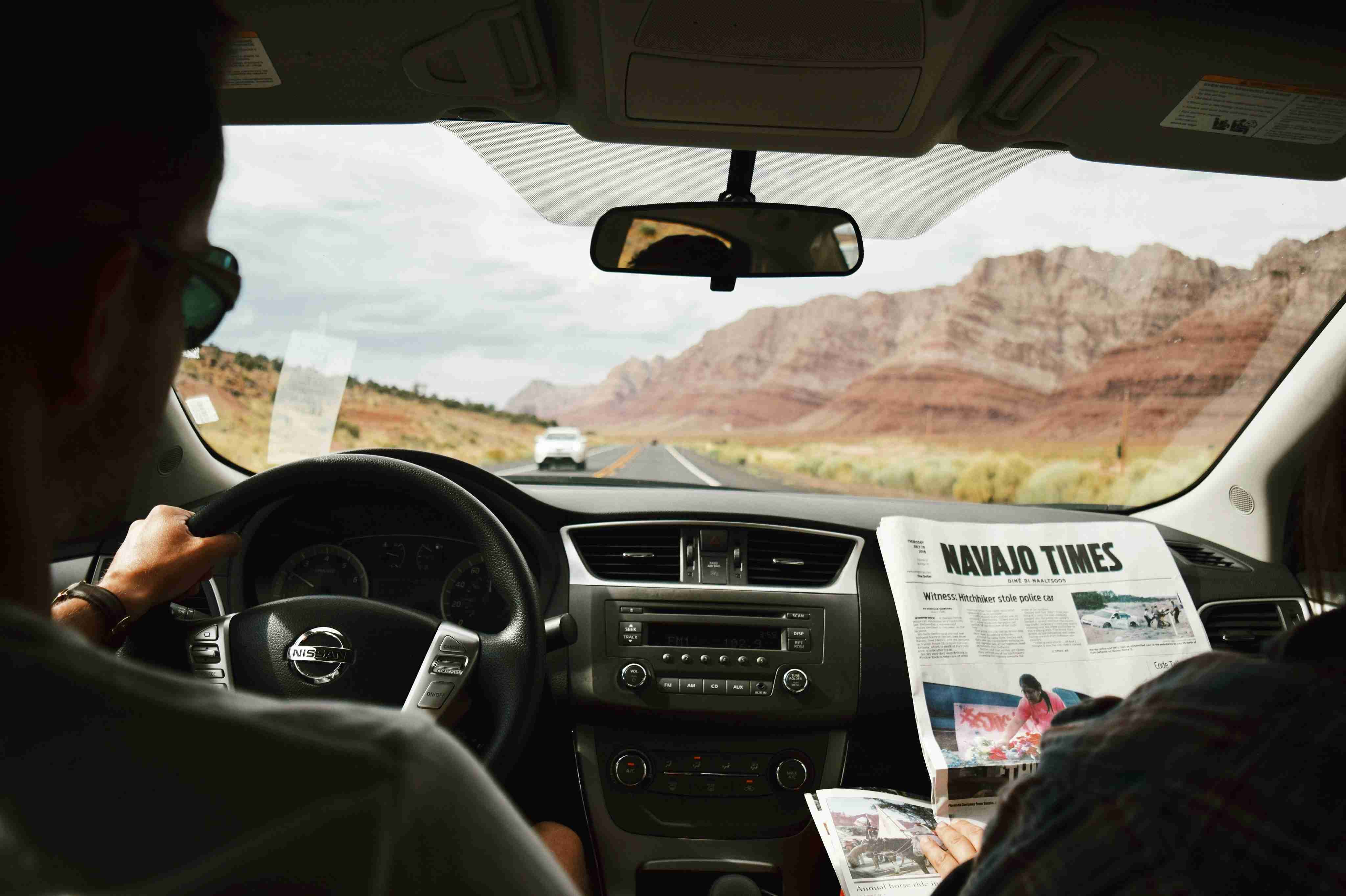a man driving a car with a newspaper in his hand