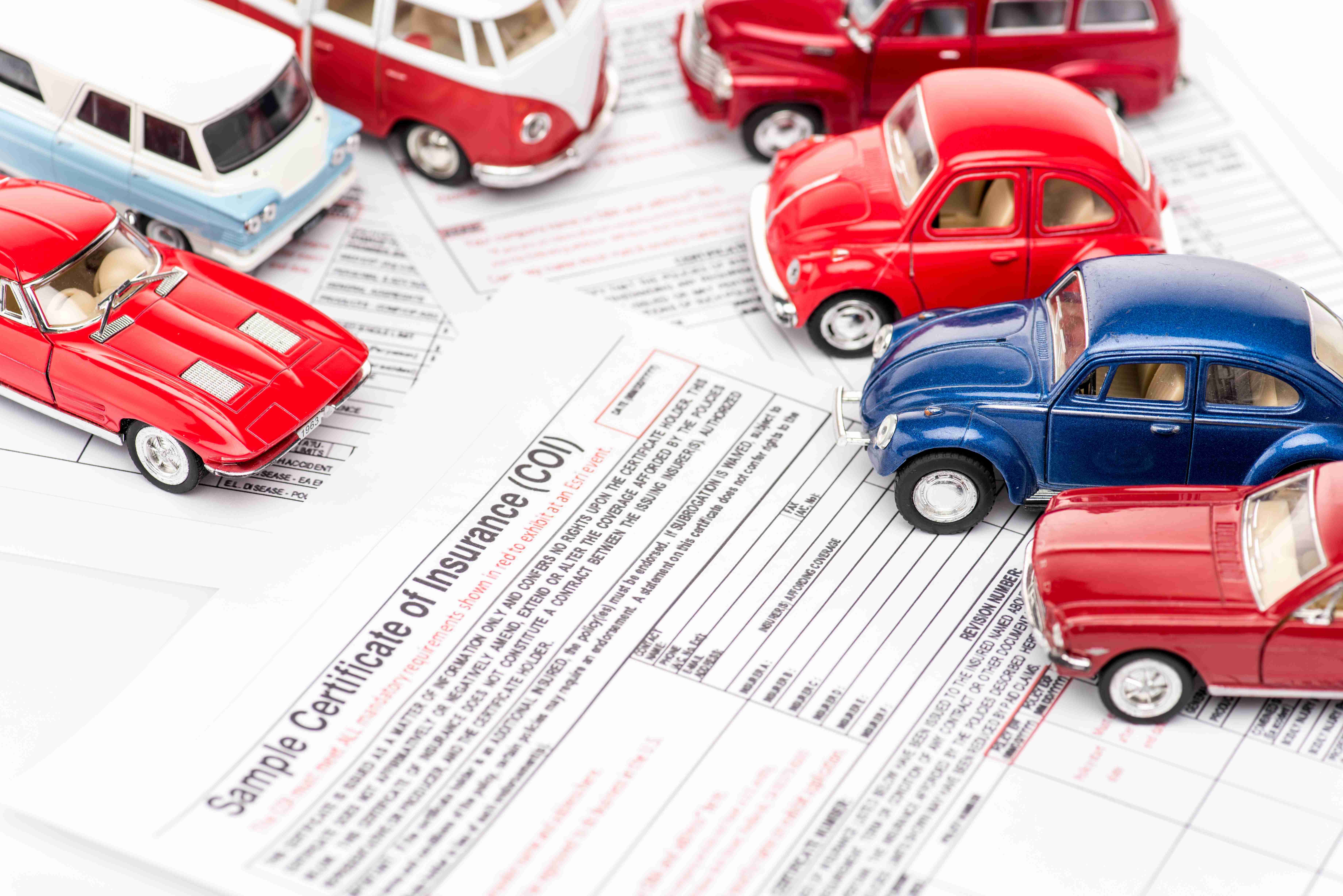 voitures jouets rouges et bleues sur des documents d'assurance