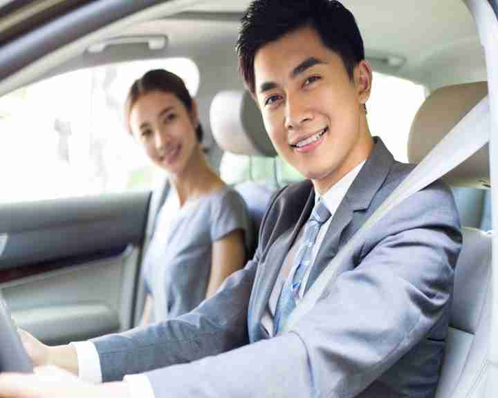 Young businessman driving car with his wife sitting next to him