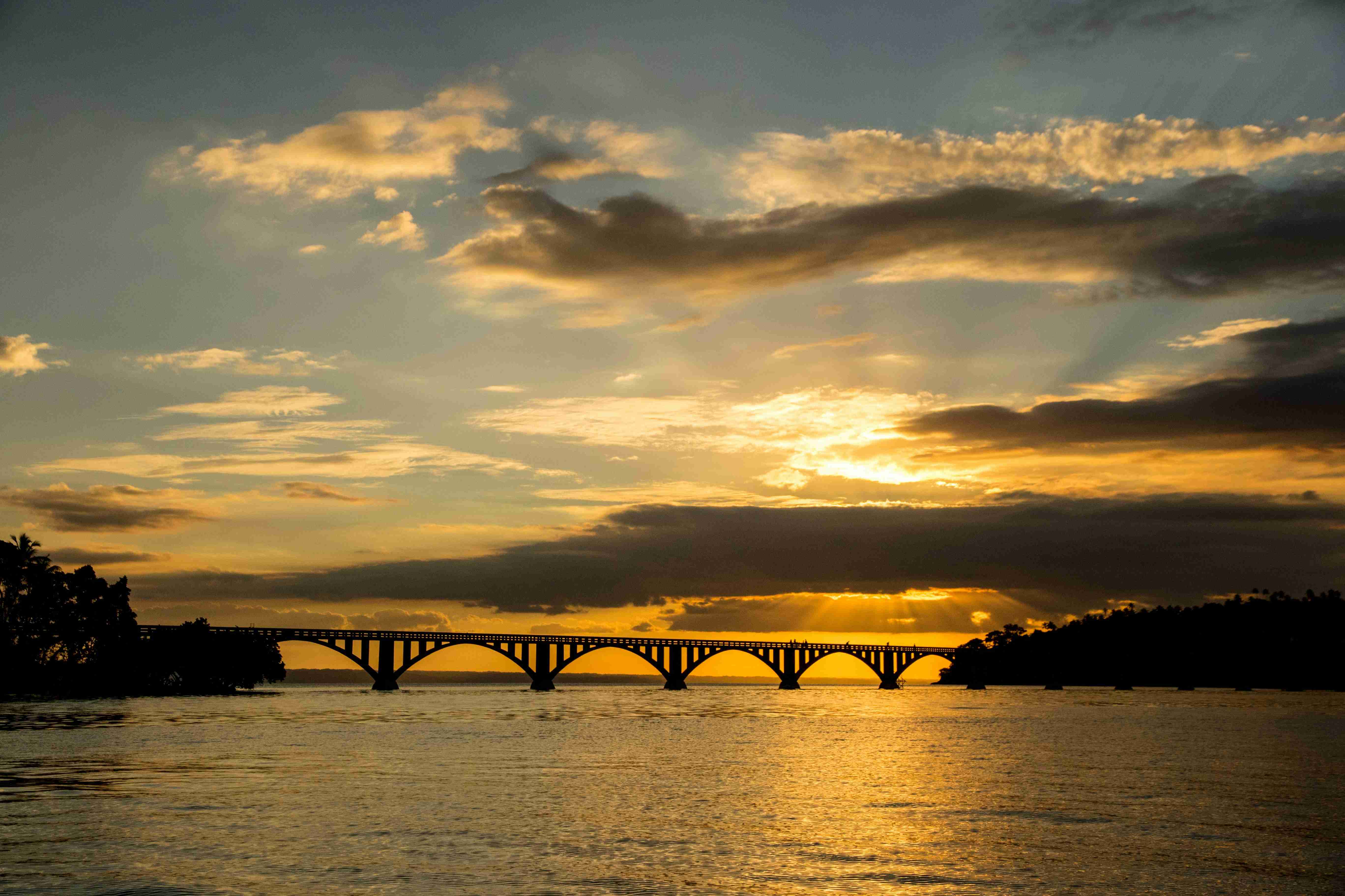the-sun-is-setting-over-a-bridge-over-a-body-of-water