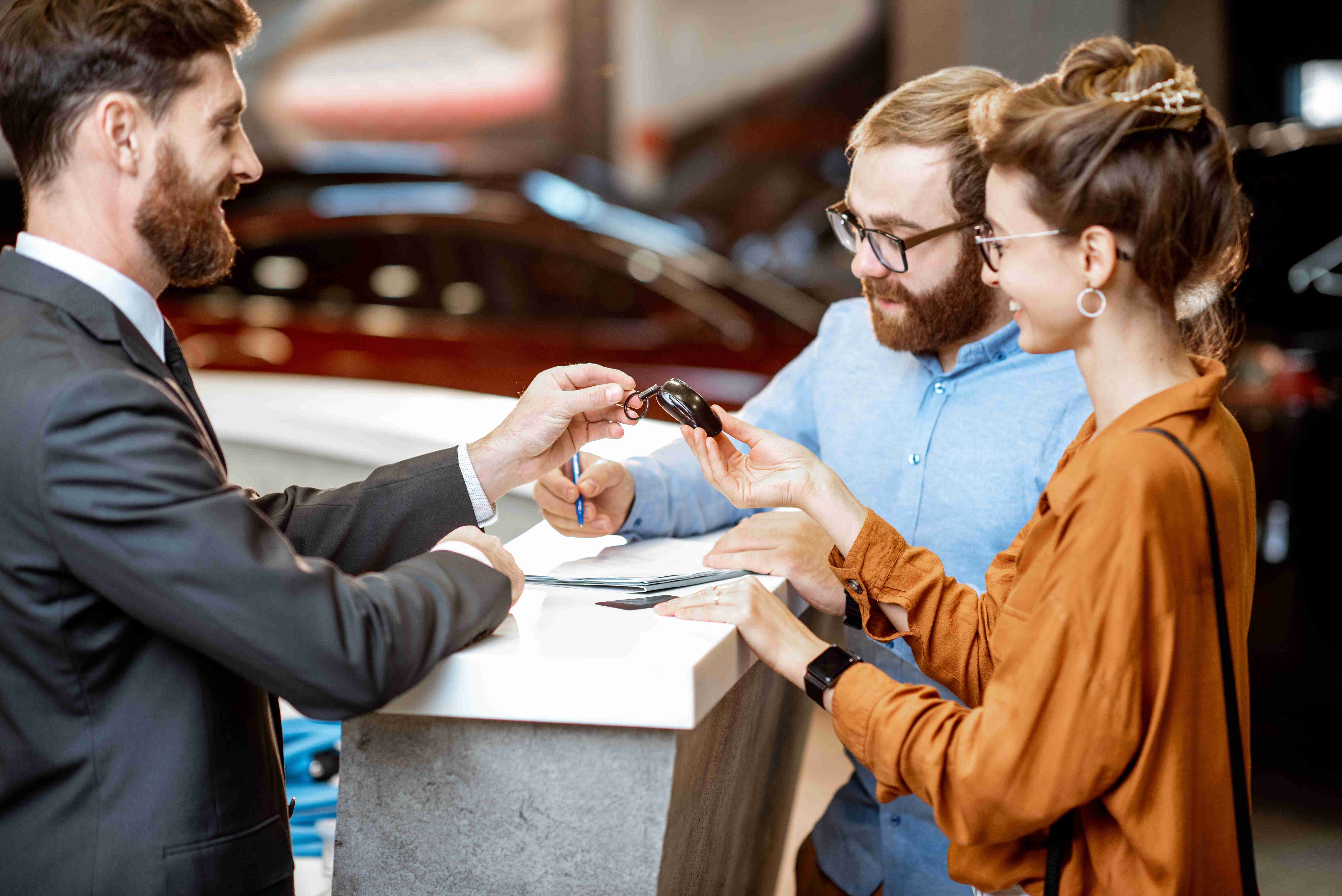 Responsable des ventes avec un jeune couple louant une voiture