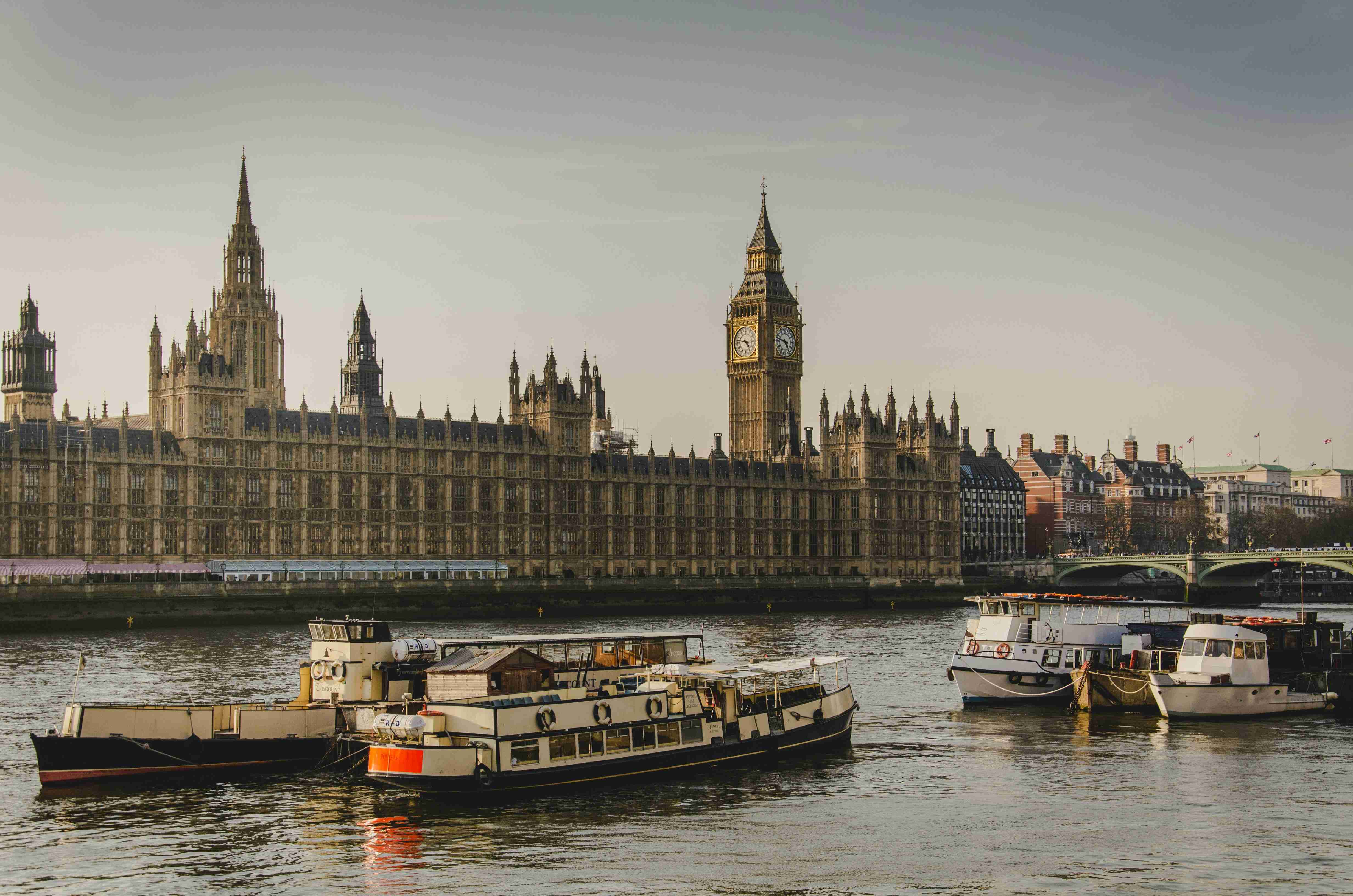 four white boats traveling on river beside big ben