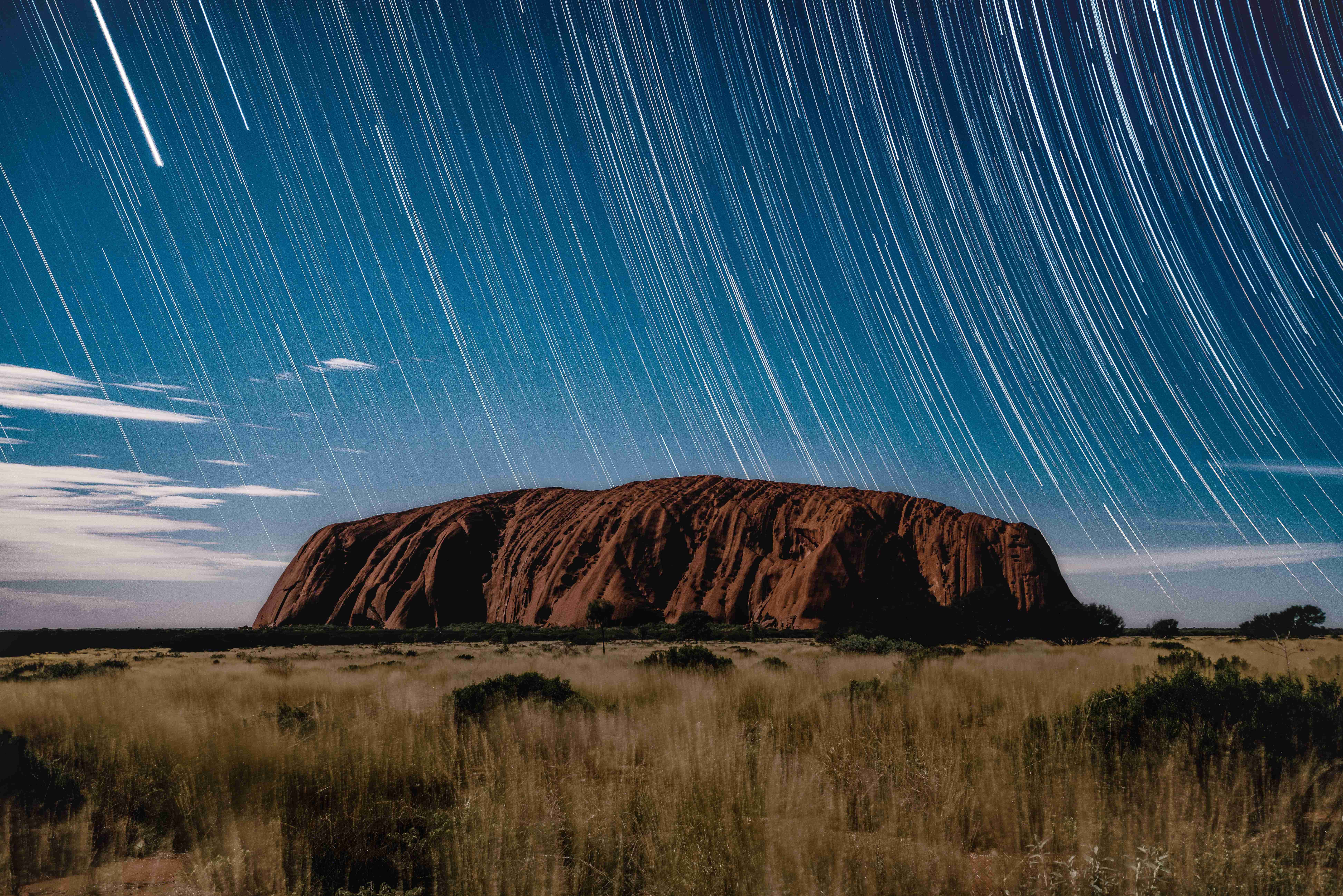 Uluru di bawah denai bintang di langit malam.