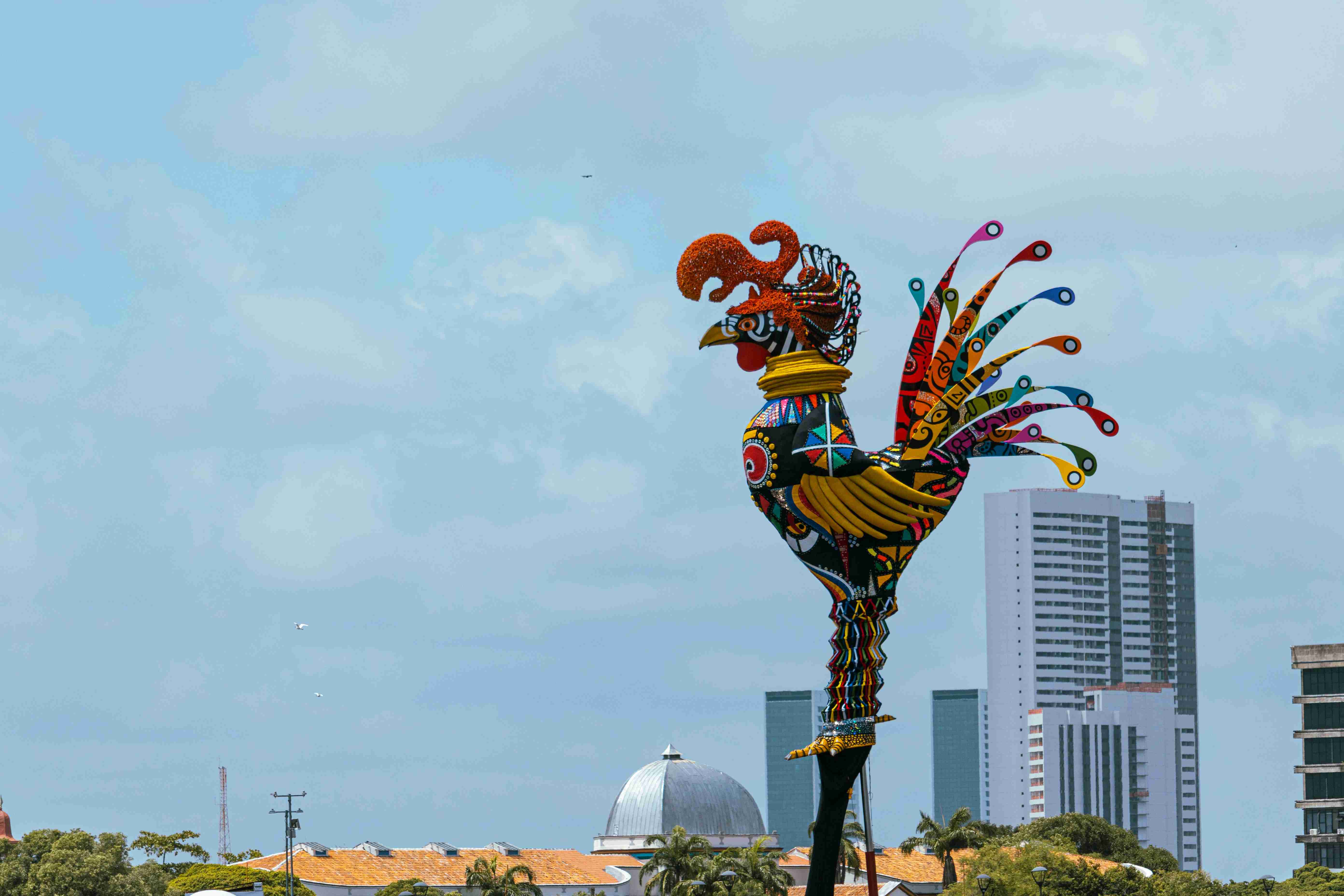 a-statue-of-a-rooster-in-front-of-a-city-skyline