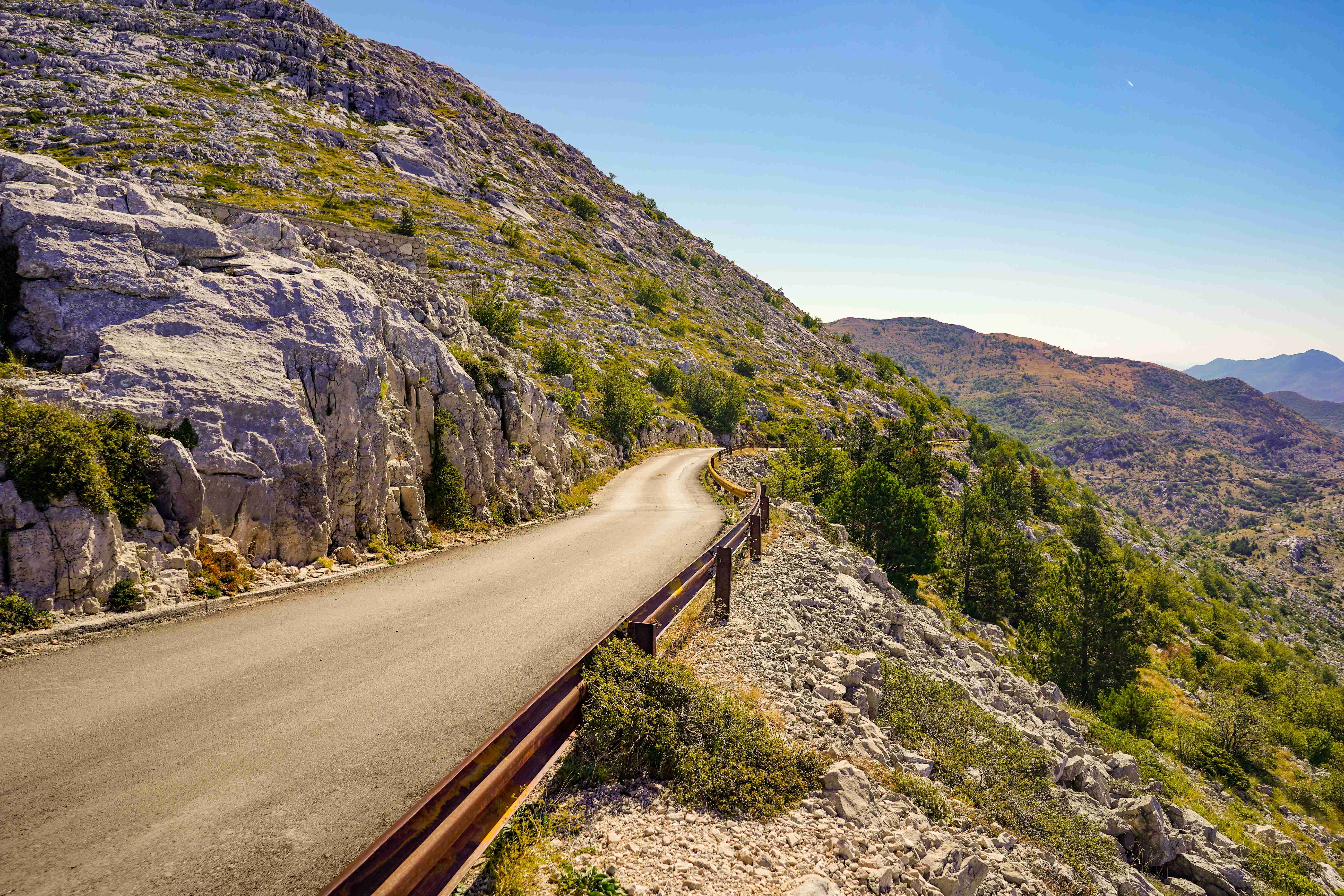 strada di cemento grigia vicino a una montagna verde e marrone