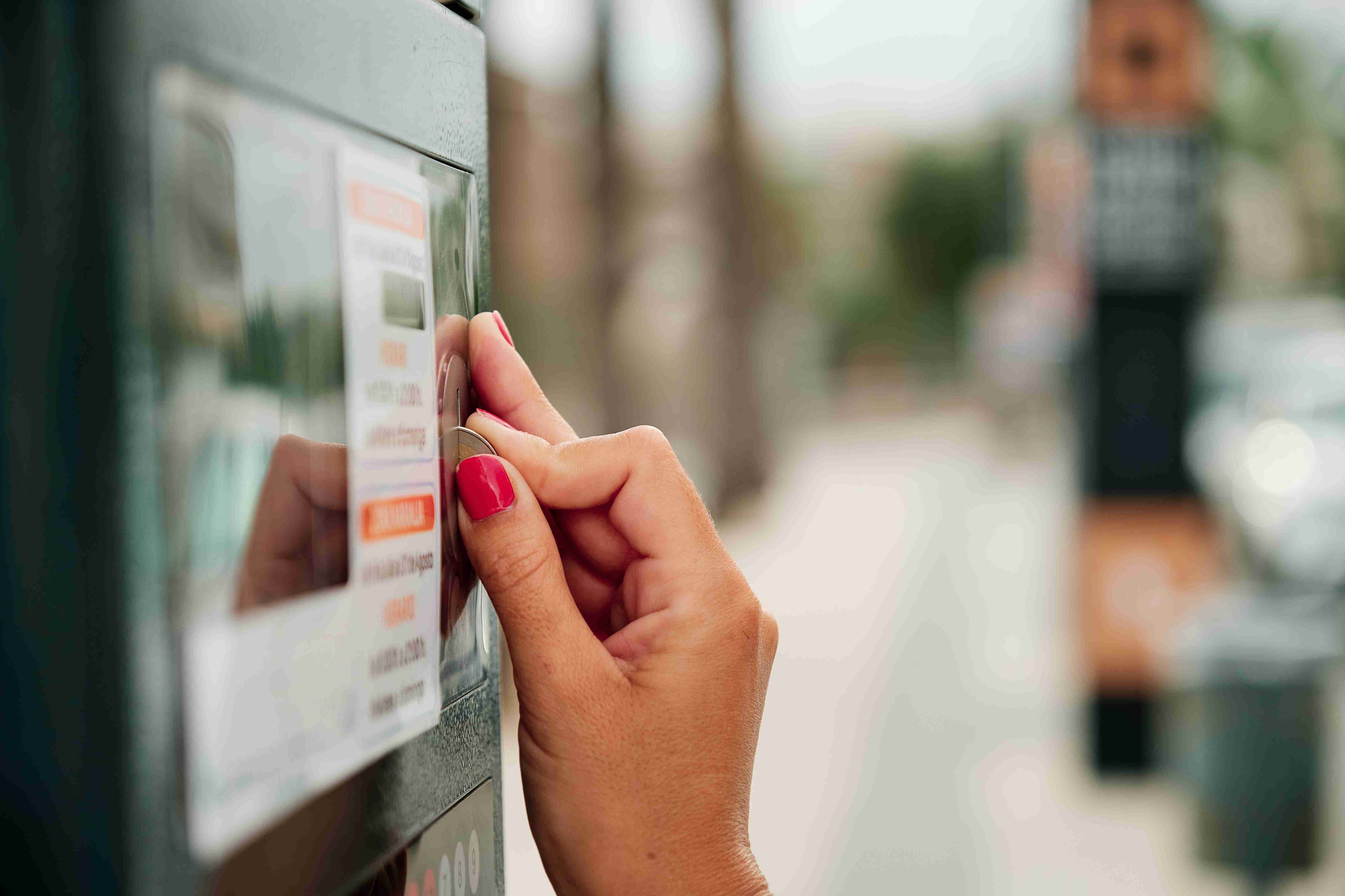 moteris rankomis naudoja monetą stovėjimo skaitiklyje